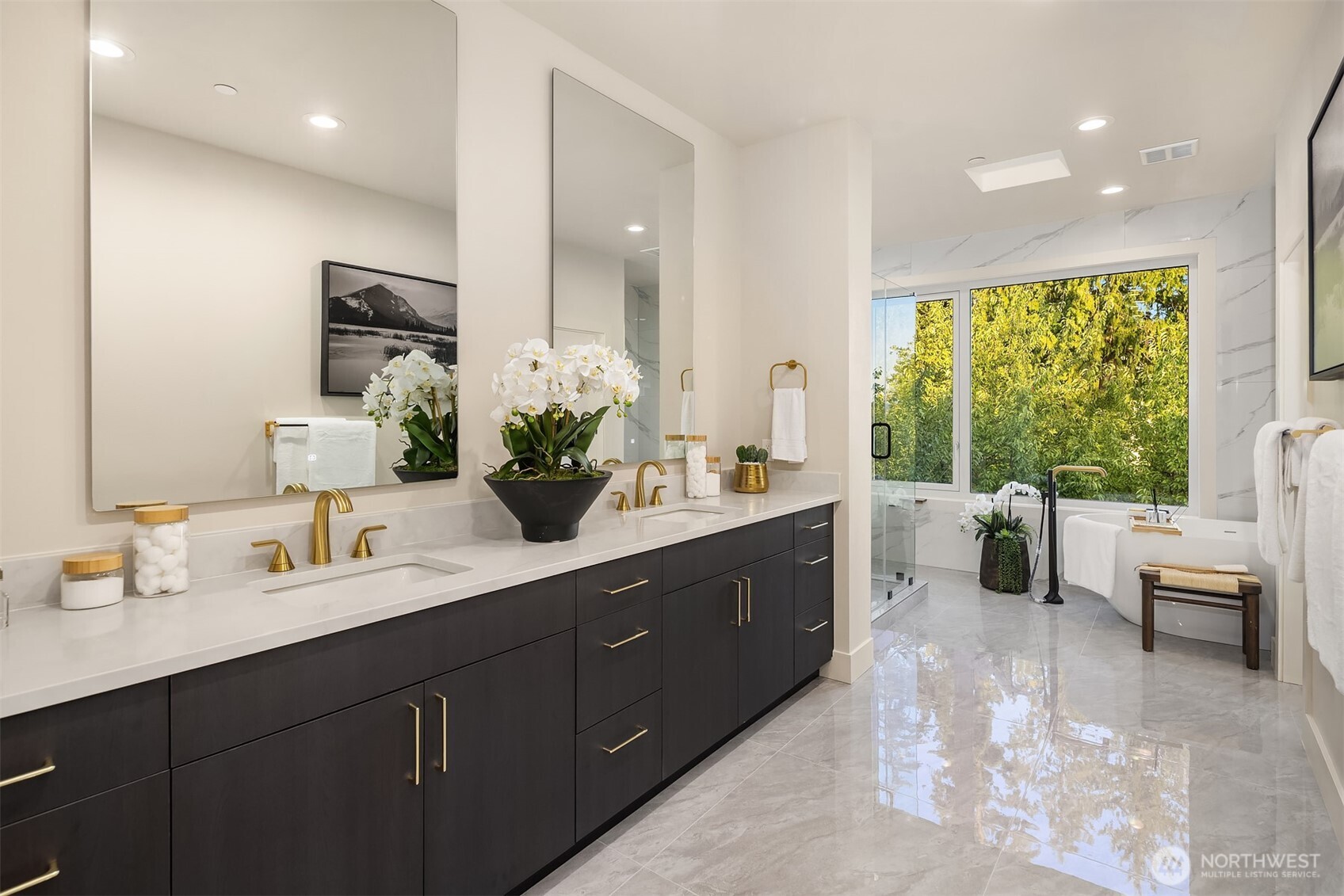Spa-inspired primary ensuite with dual vanities, luxe finishes, and a soaking tub framed by serene treetop views