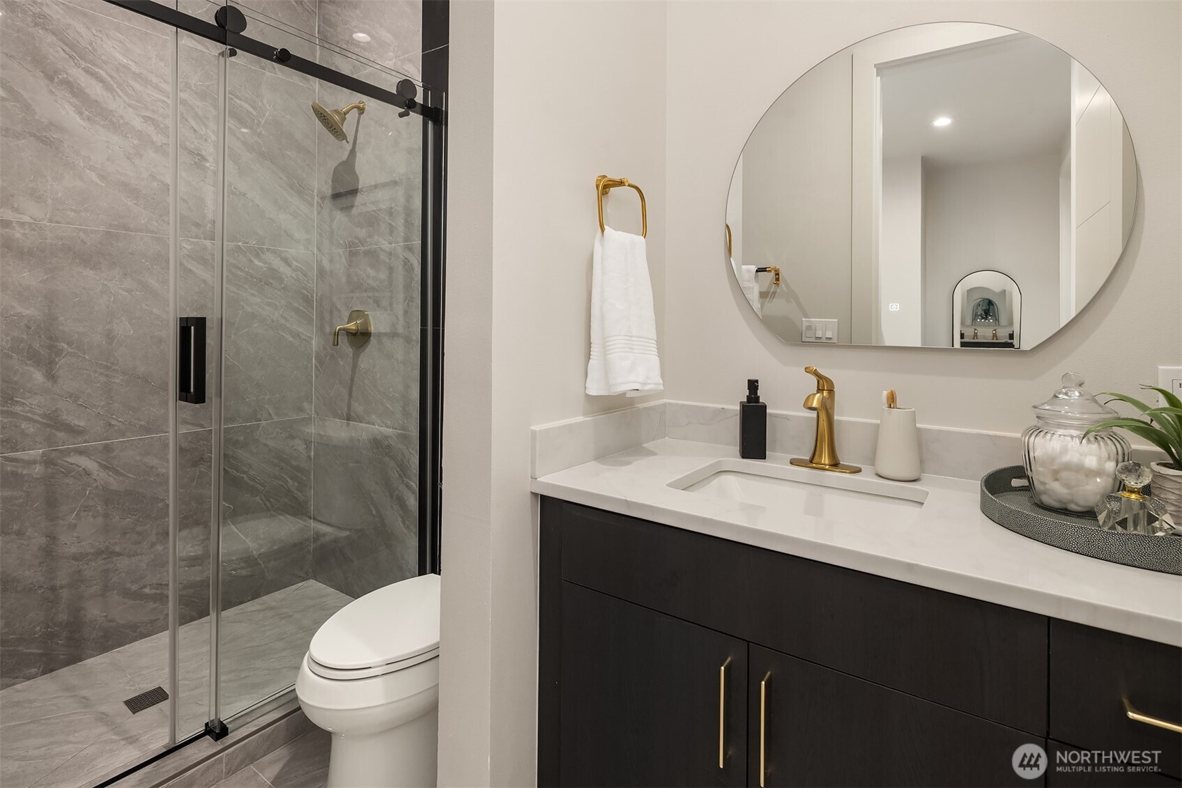 Ensuite bath with sleek stone tile, brushed gold fixtures, and a picture window bringing in natural light