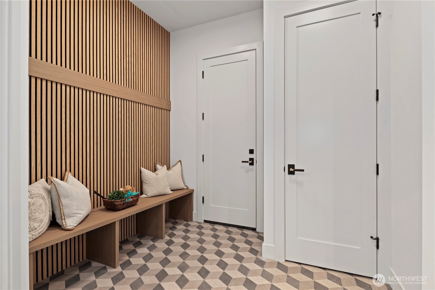 Thoughtfully designed mudroom with custom bench, 3D geo tile floor pattern, slat accent wall detail, coat hooks (will be installed, and coat closet. .
