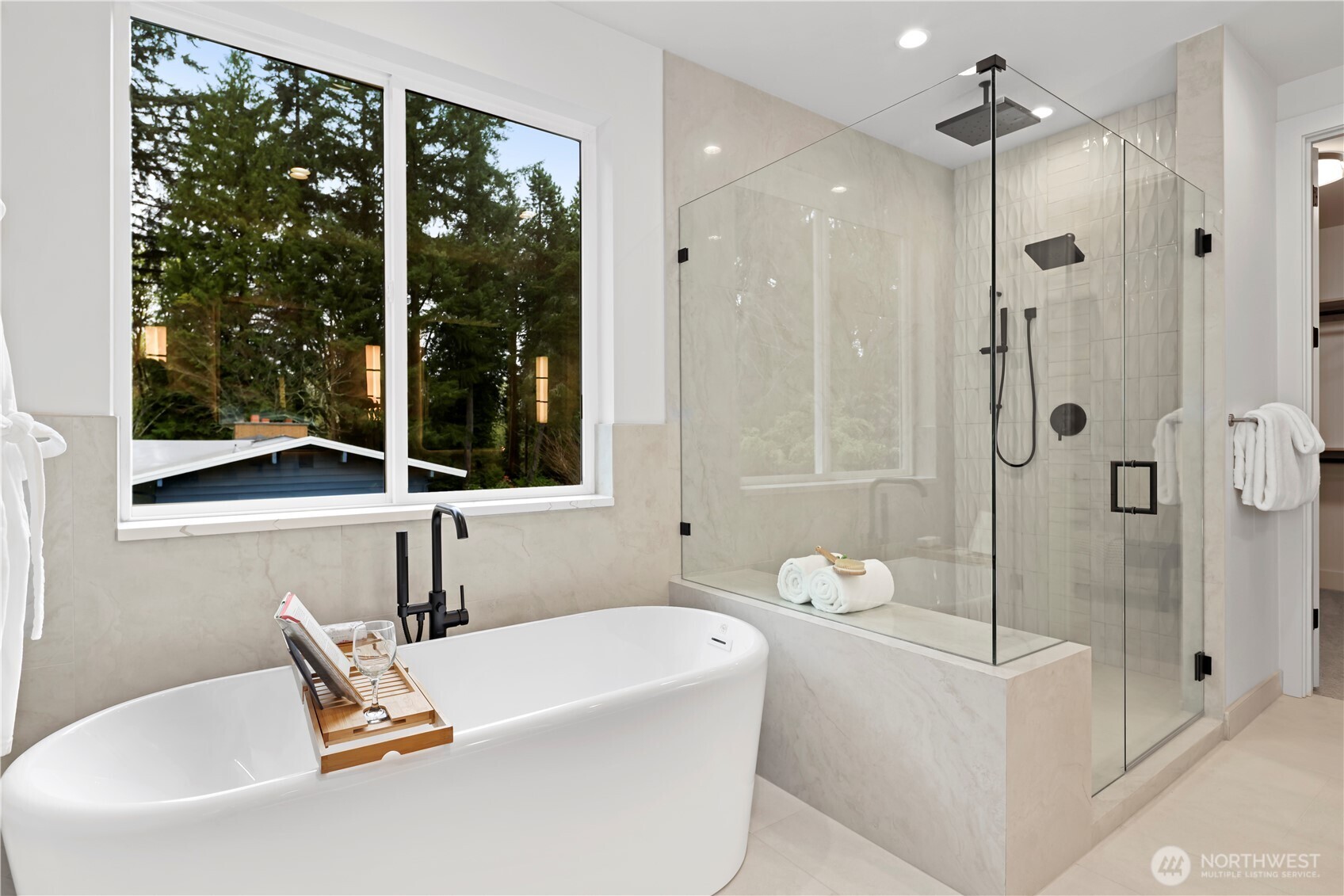 Freestanding soaking tub set beneath a picture window with tranquil treetop views. Walk-in shower has a dynamite bench seat, shampoo niche, and cozy heated-tile floors.