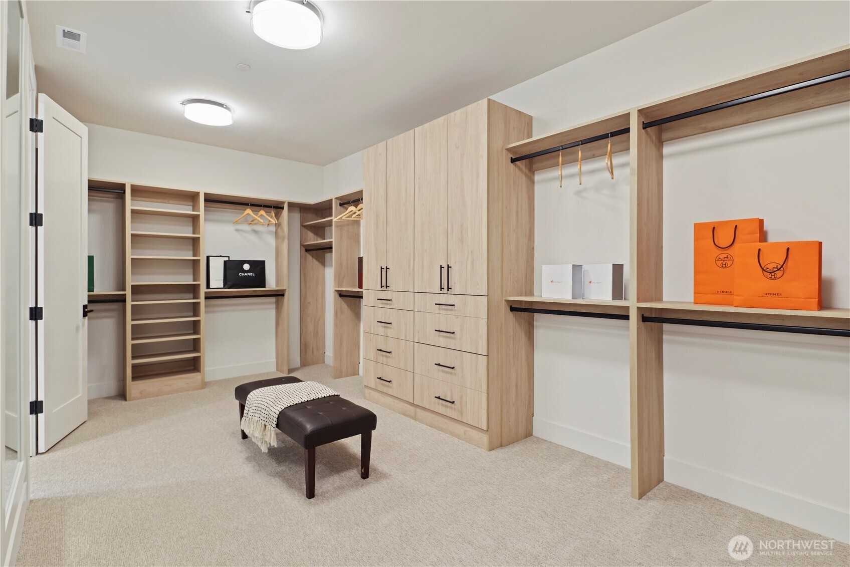 Huge custom walk-in closet with armoire-style cabinets, built-in drawers, open shelving and hanging options, plus a full-length wall mirror.