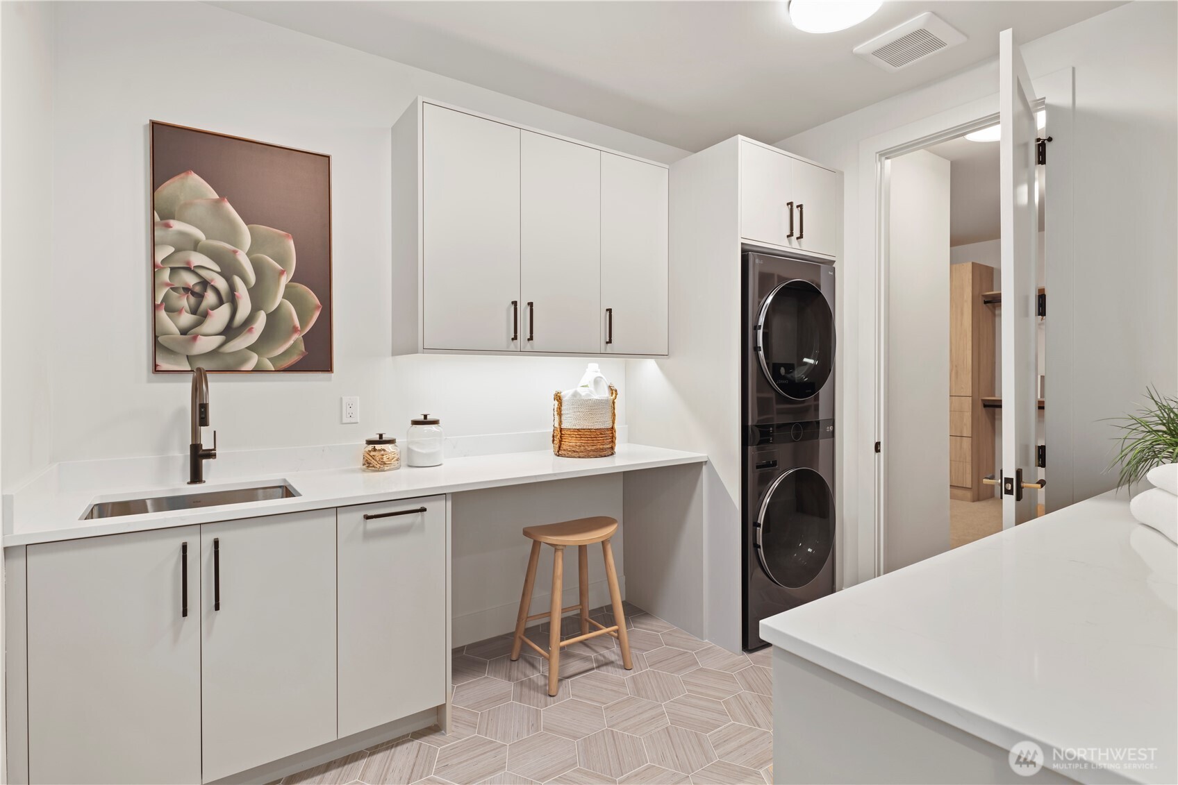 Well-appointed laundry room with bells and whistles: based and upper cabinets, LG stacked washer and dryer, stainless utility sink with pull-out sprayer, pull-out garbage, built-in slab quartz folding counters, under cabinet lighting, and toe-kick motion sensor. Laundry directly connects to the primary walk-in closet.