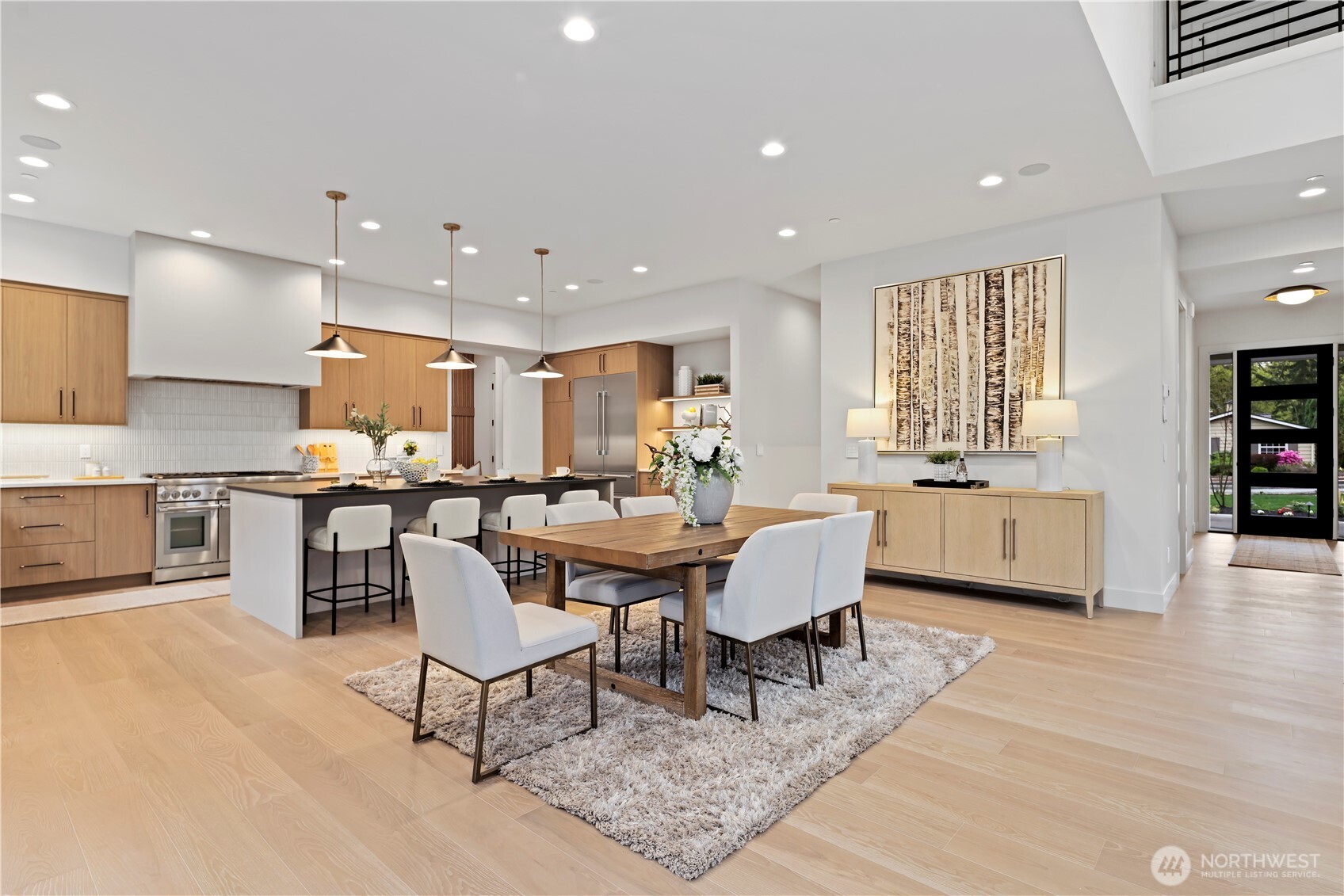 Open informal dining flows to chef’s kitchen with oversized island, warm wood cabinetry and backyard access.
