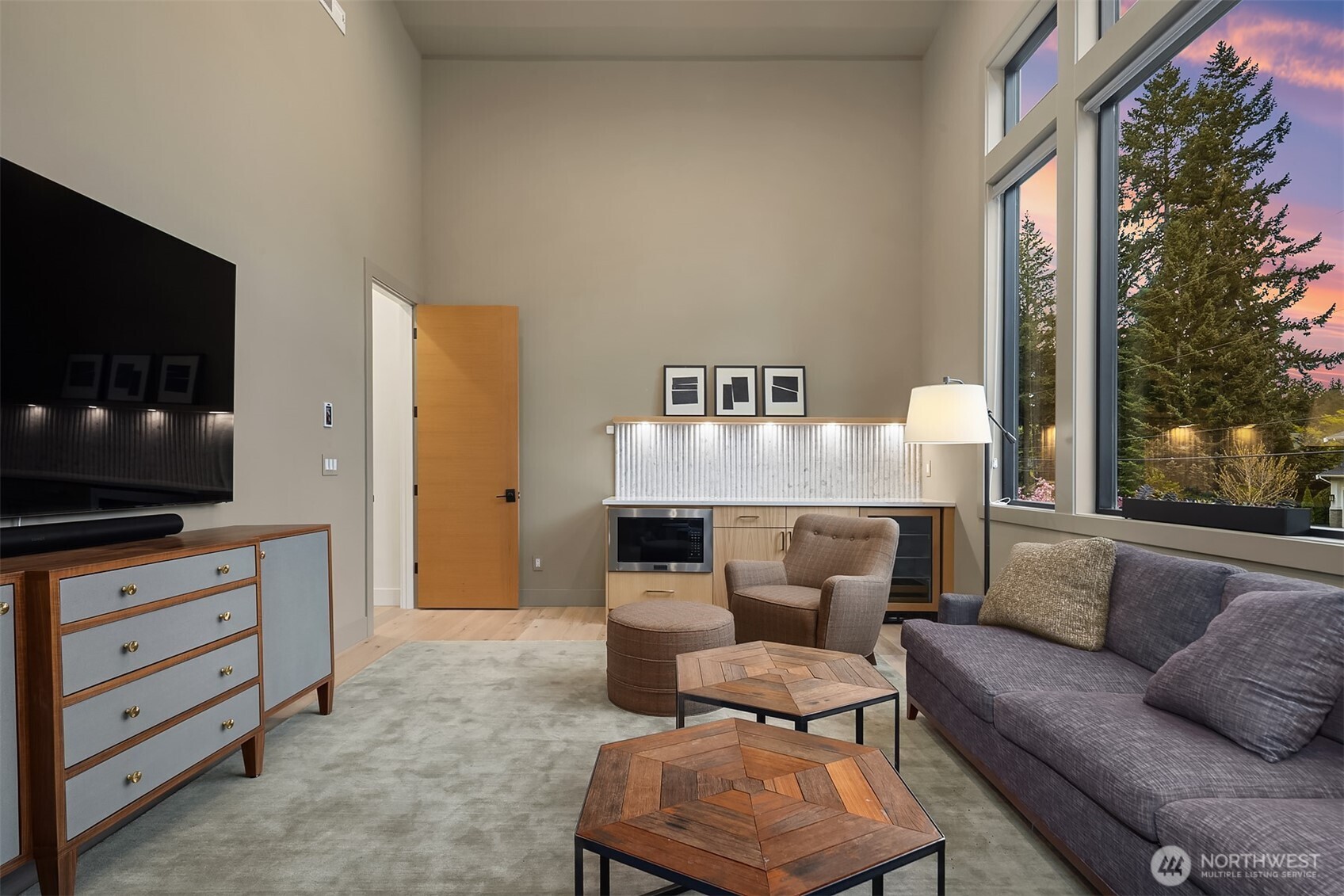 A vaulted bonus room with soaring ceilings, a built-in wet bar, and a wall of windows. Media room, playroom, second living space — it works equally well as all three.