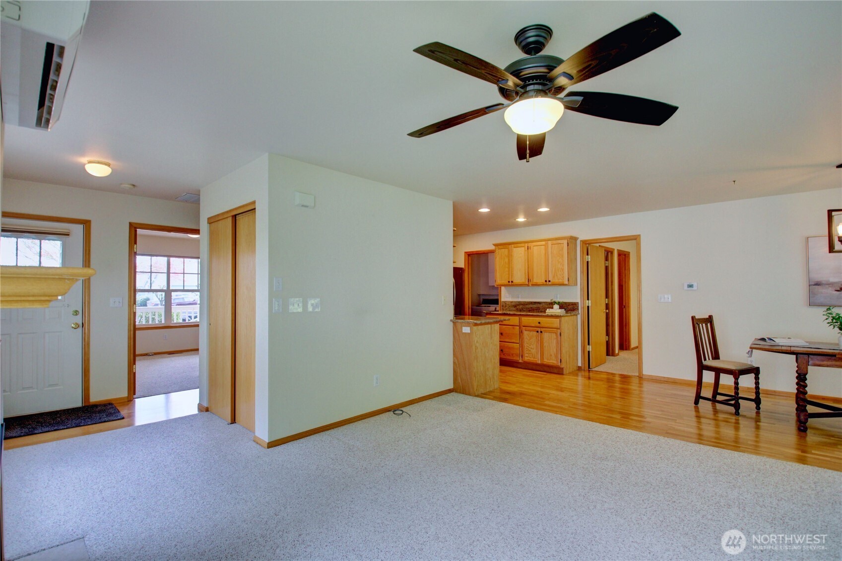Looking from the living room to front door, 2nd bedroom, coat closet and into kitchen.