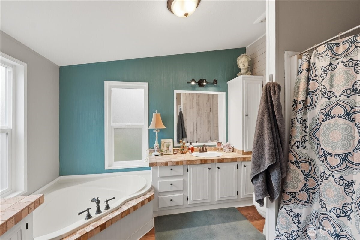 5-fixture primary bath with double vanity, large soaking tub and separate showing.