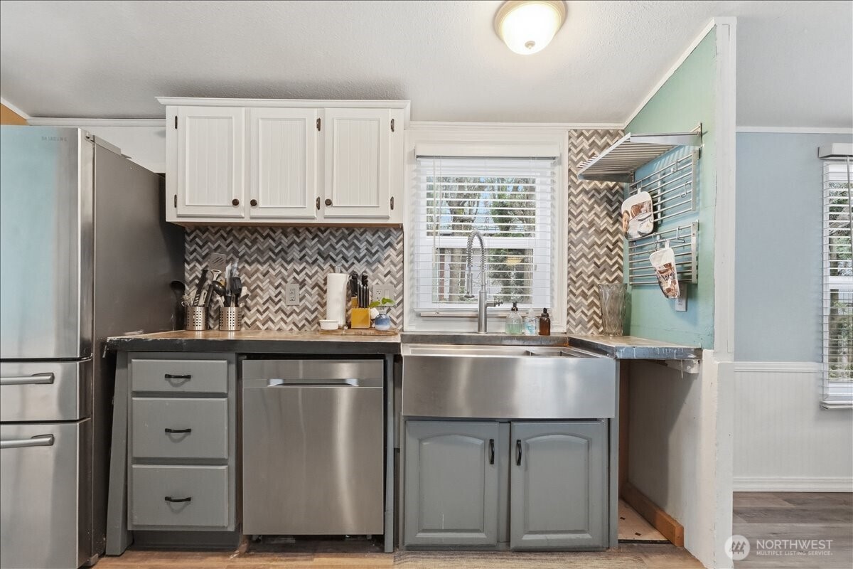 Kitchen with stainless steel appliances, farm sink and updated tile backsplash.