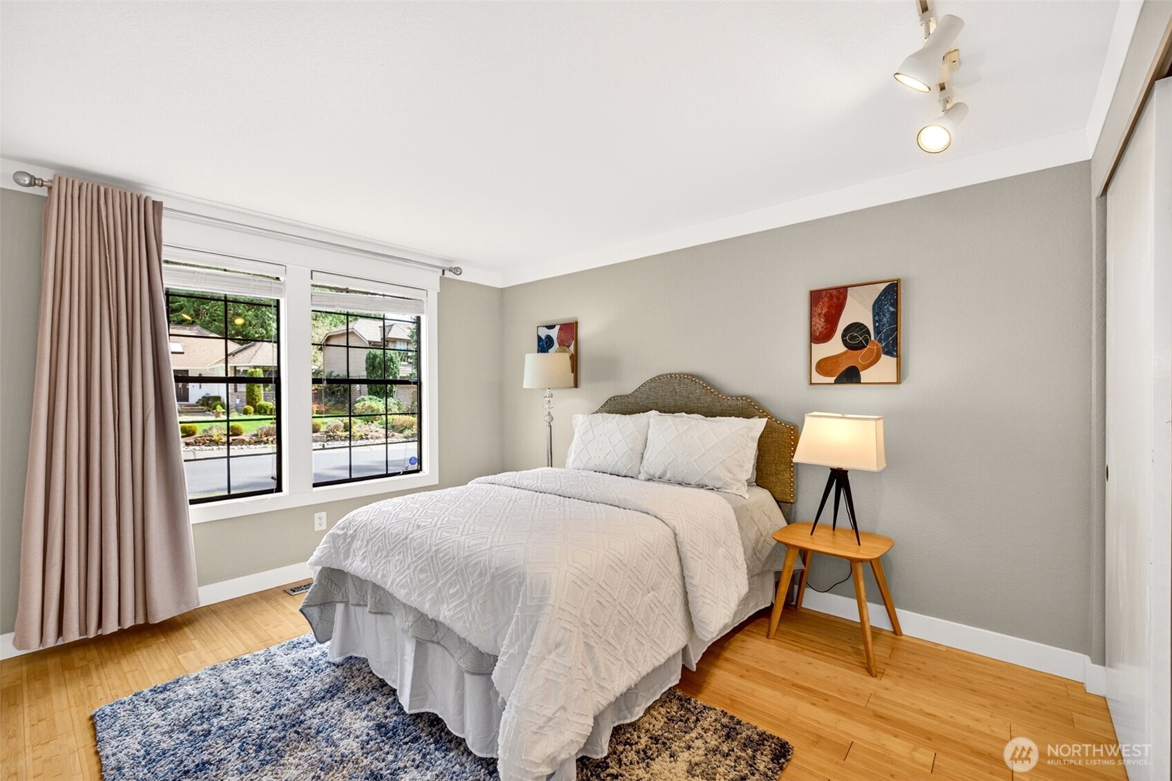 A bright main-floor bedroom with oversized windows offers garden views and the convenience of single-level living for guests, family, or a private home office.