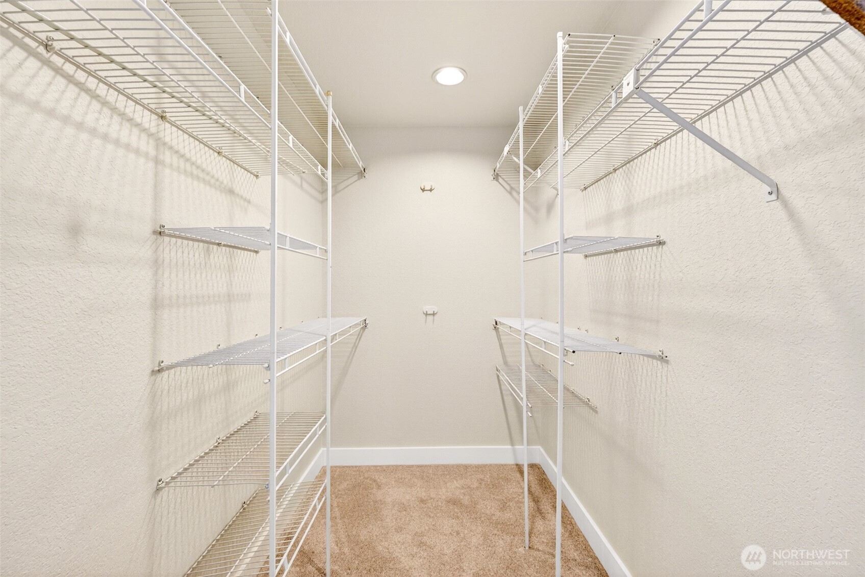 A spacious walk-in closet with custom shelving on both sides delivers the kind of dedicated storage that makes daily routines effortless.