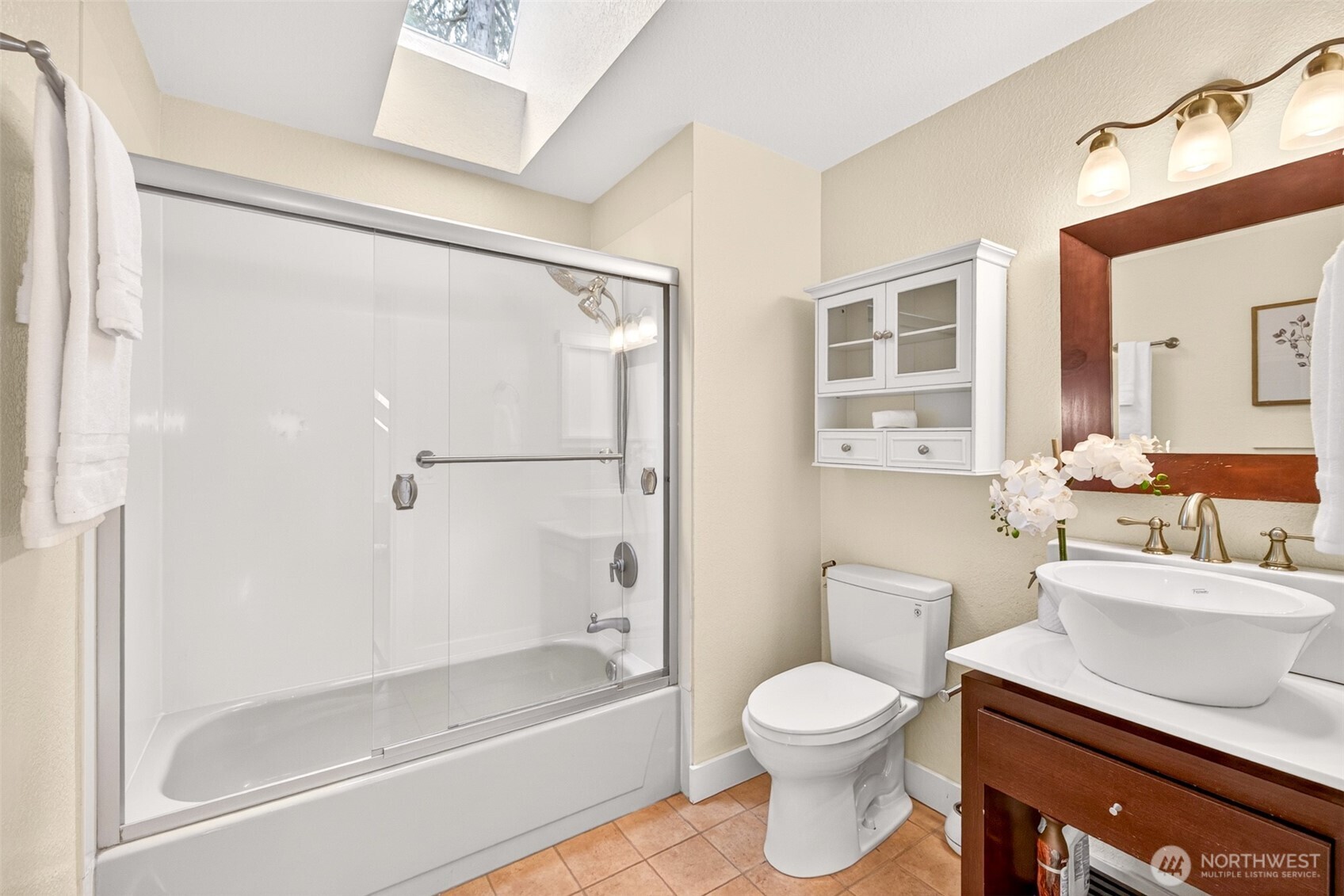 The primary full bath features a tub-shower combination, vanity with vessel sink, and a skylight overhead that bathes the space in natural light all day long.