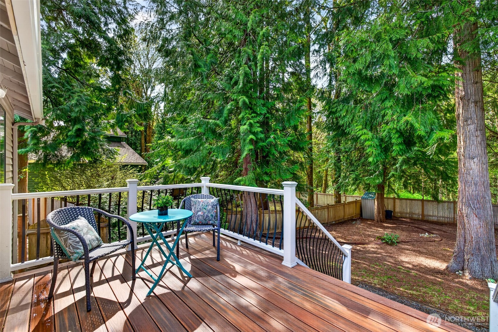 A peaceful back deck overlooks a private, evergreen-lined backyard, the perfect spot for morning coffee or quiet evenings surrounded by nature.