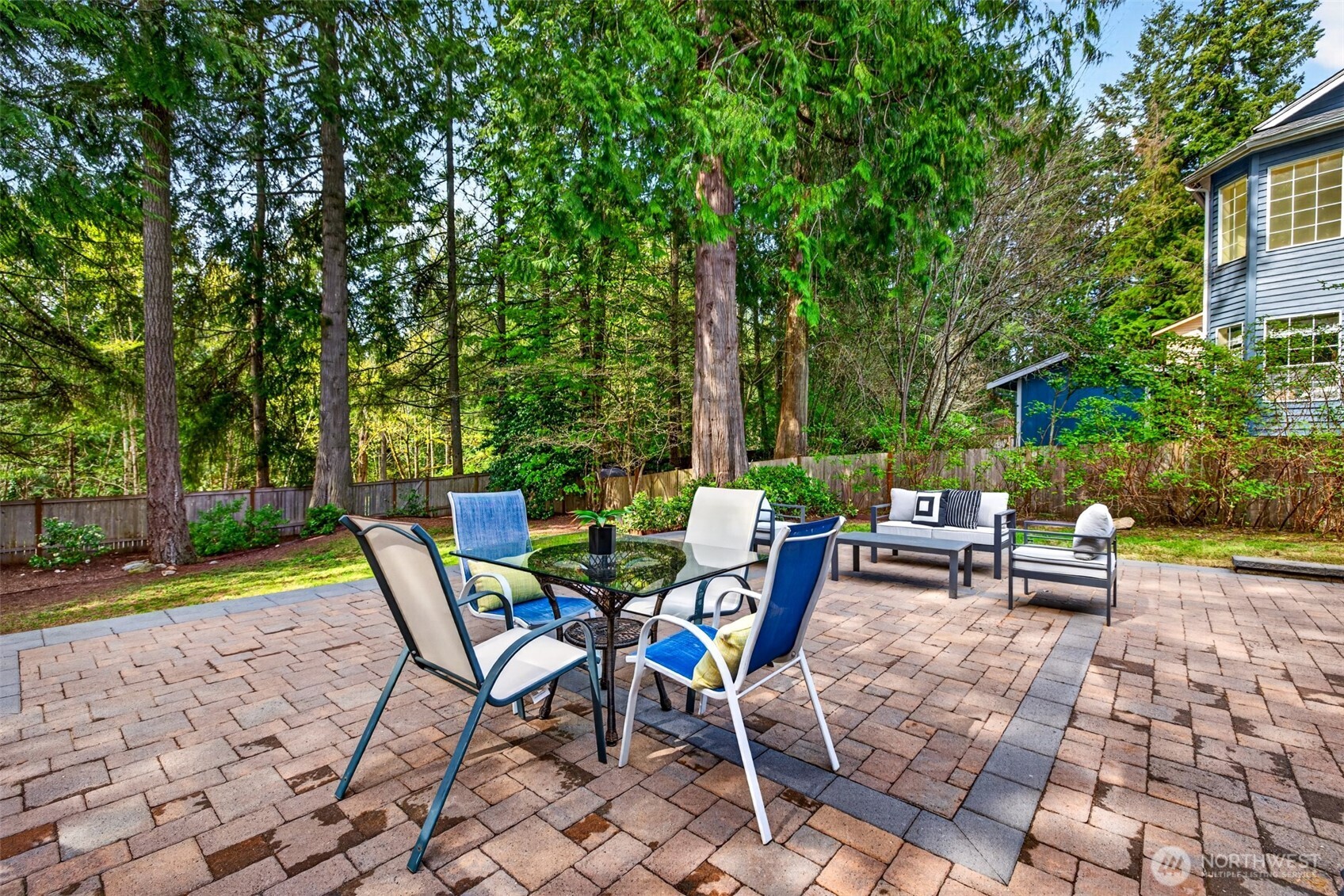 The new stone paver patio offers generous room for al fresco dining and conversation seating, framed by mature evergreens and a private fenced setting tailor-made for memorable gatherings.