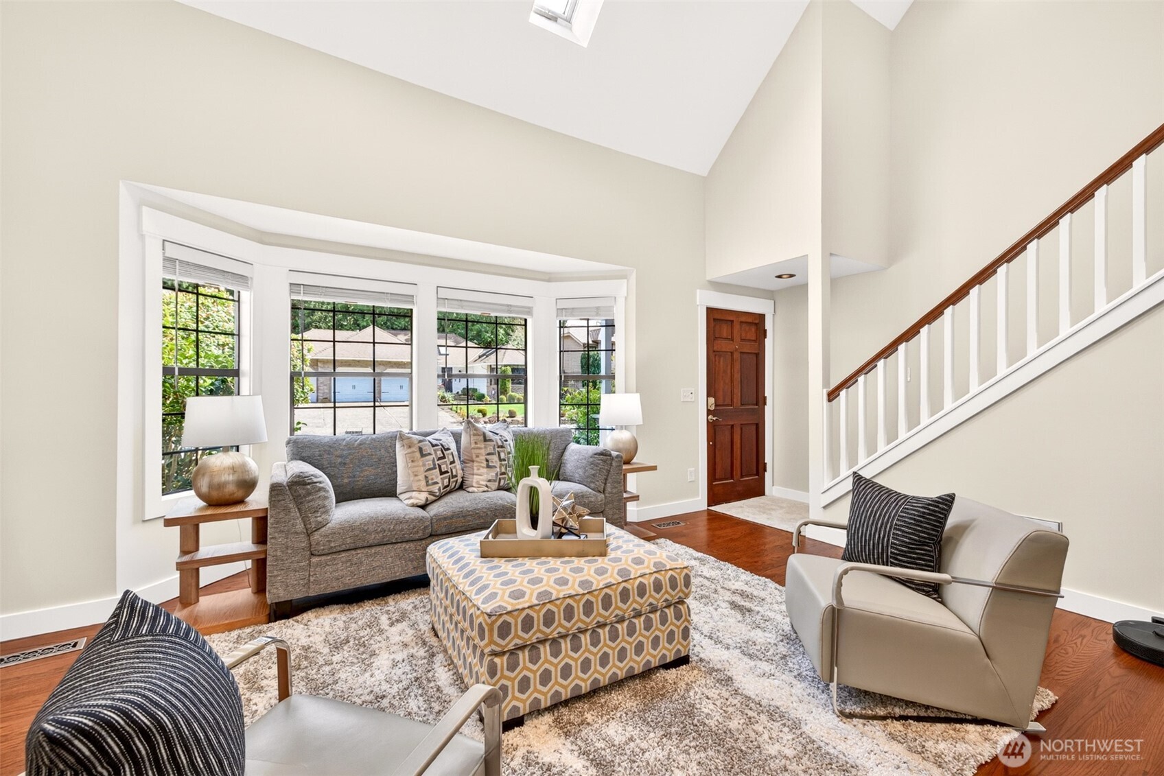 Two-story ceilings and a wall of windows flood the front living space with natural light, delivering immediate volume and warmth from the moment you step through the door.
