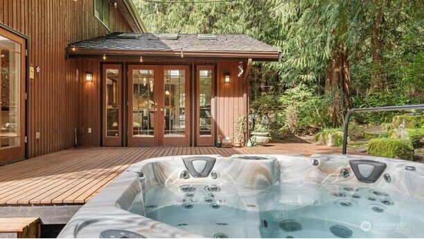 French doors on both sides and picture windows that frame the forest so beautifully make the connection to the outdoors unmistakable here. Just beyond, the deck stretches across the back of the home, extending the living experience into the peaceful wooded setting.