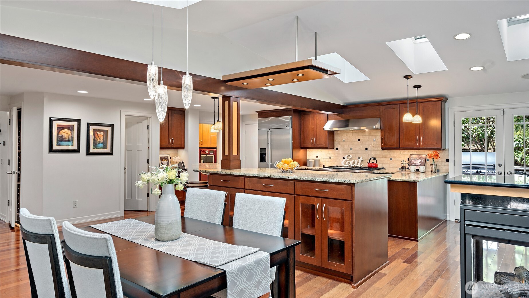 The three-sided glass fireplace brings both warmth and beauty to the space, while the custom burled maple and glass pendant chandelier adds such a striking, artful presence overhead. Together, they make this room especially memorable.