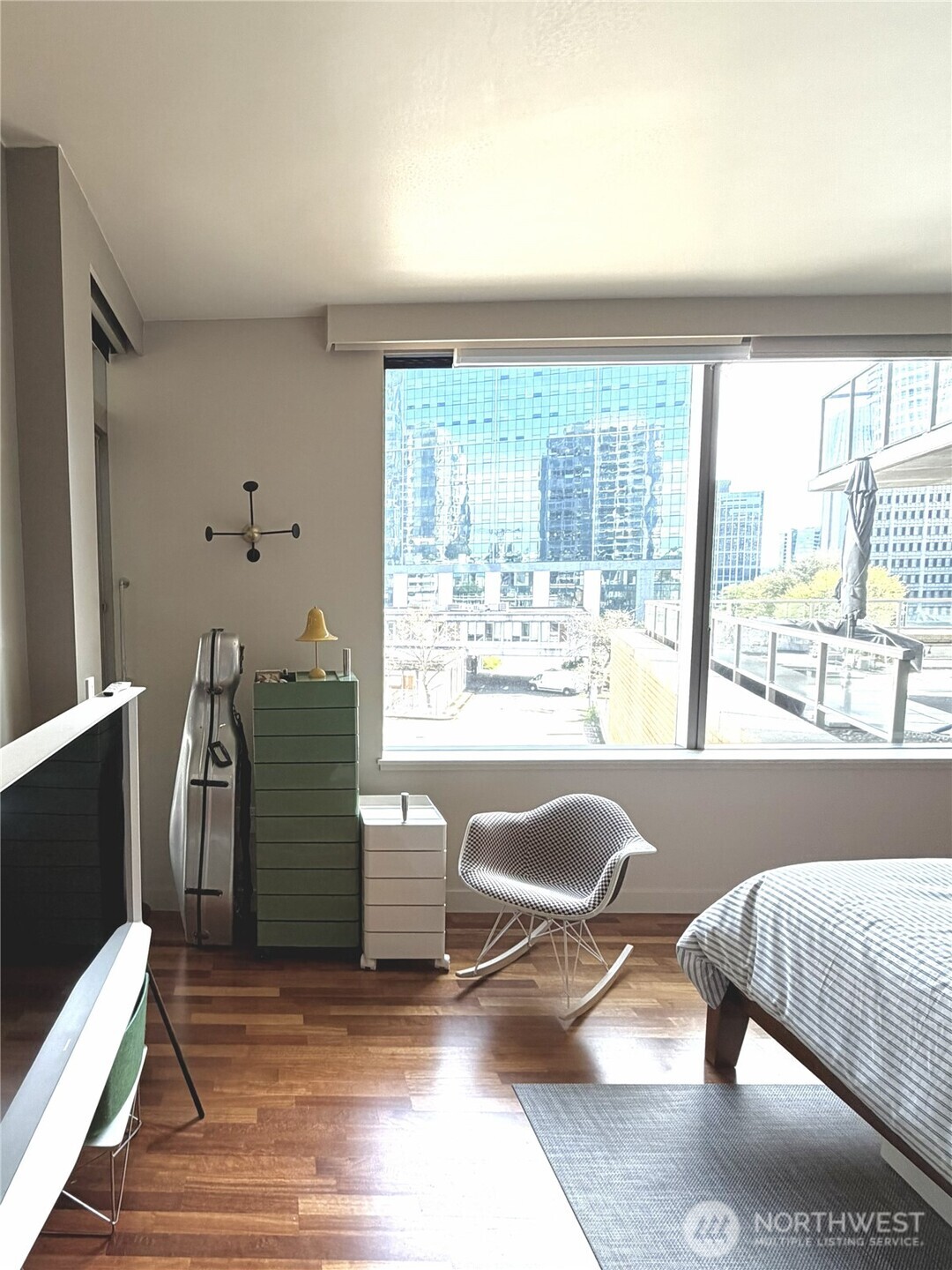 Bright bedroom with large windows and city views.
