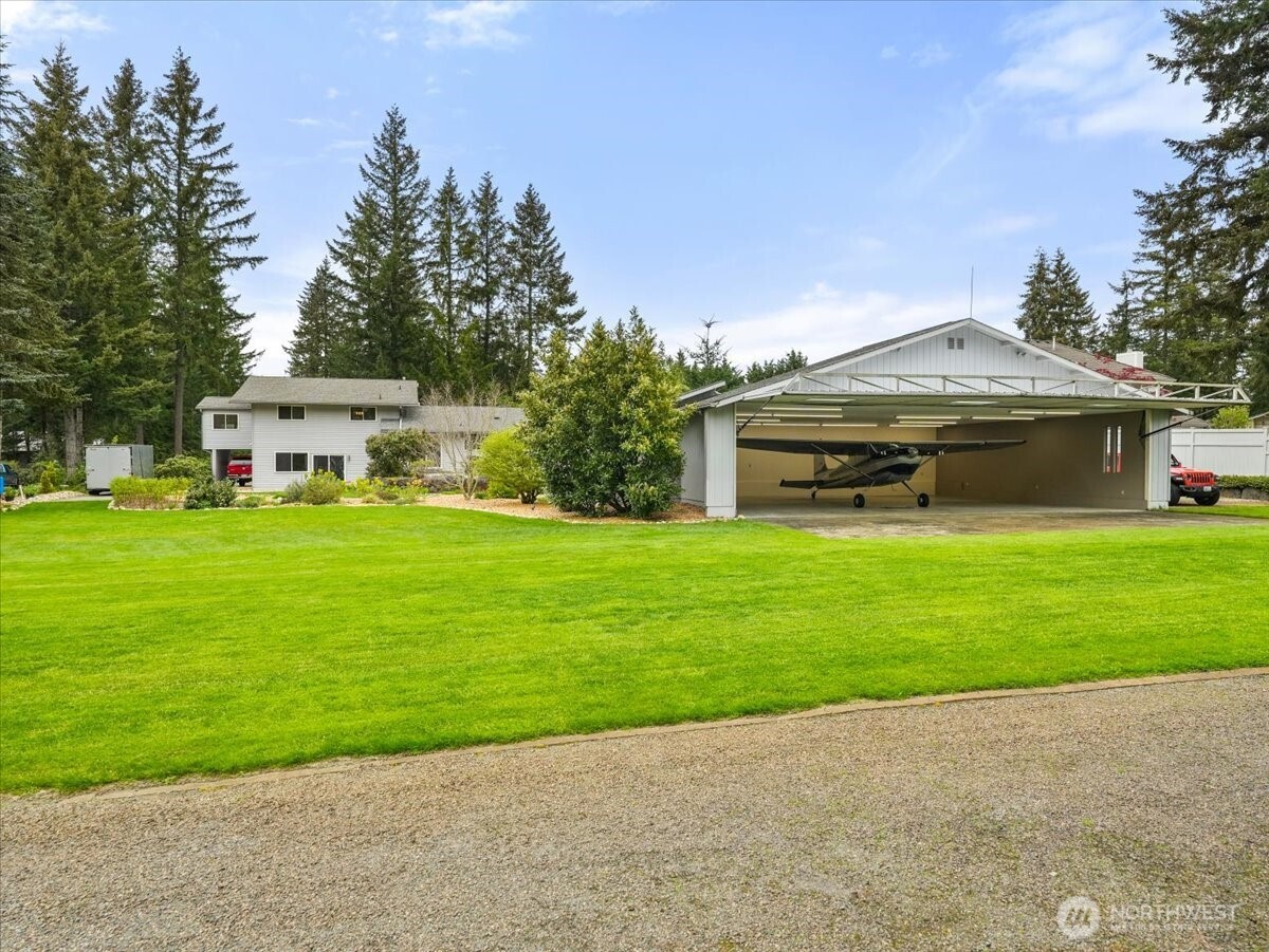 View frrom a neighboring yard: lush, grassy taxiway H, your lawn, and your own hangar.