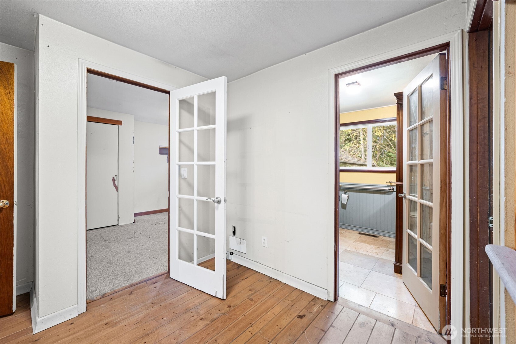 Connecting hallway with French doors offers flexible use as a home office or bonus space. Easy flow between bedrooms and living areas.