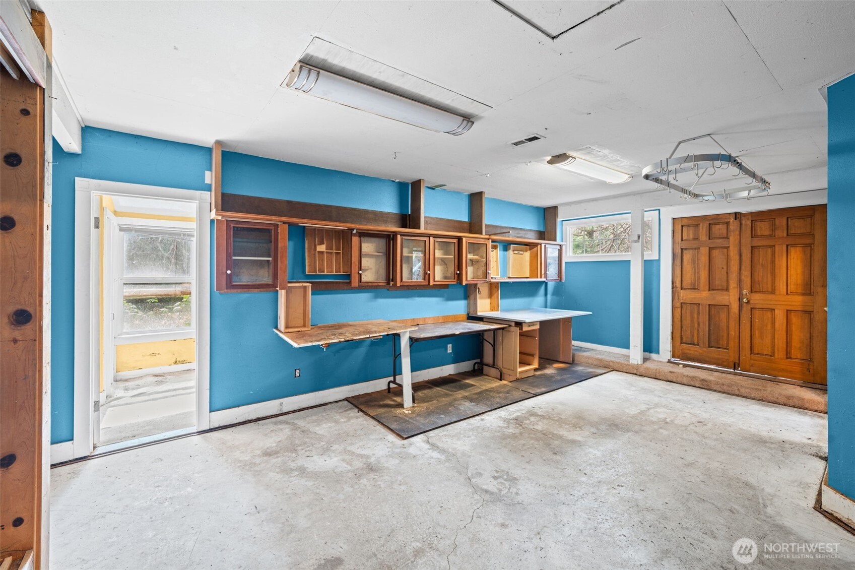 Large open space with workbench and storage cabinetry, ideal for workshop or creative studio use. Ready for updates to maximize versatility and value.