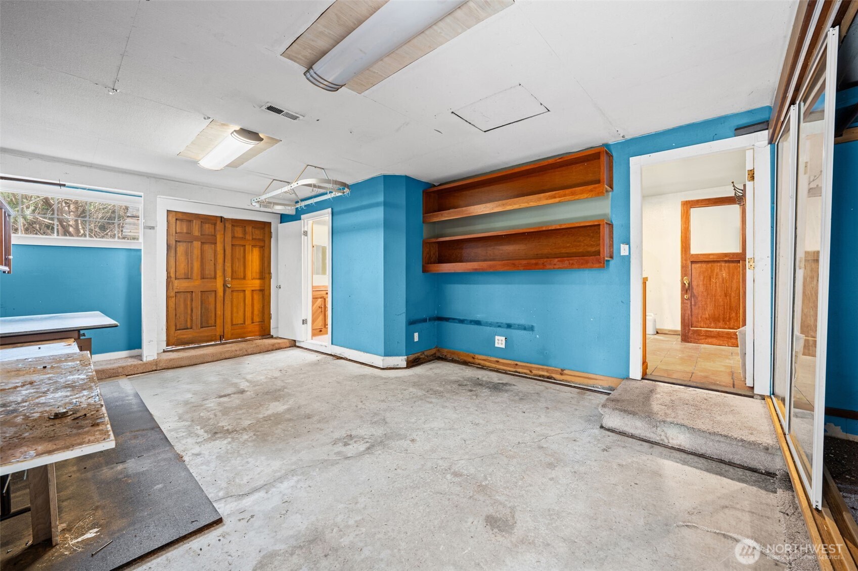 Spacious rec room with built-in shelving and direct access to adjacent areas, offering flexible use for hobbies or workspace. Great potential to transform into a functional bonus living area. Here you can see the three-quarter bath to the right.