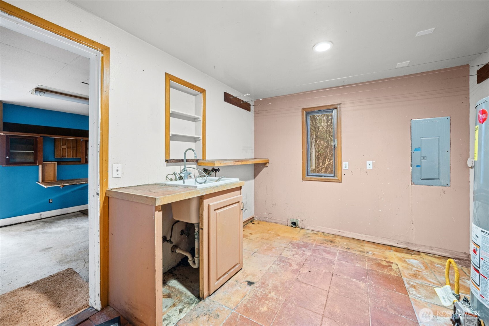 Utility room with sink, storage space, and room for laundry setup. Functional area ready for updates and improved efficiency.