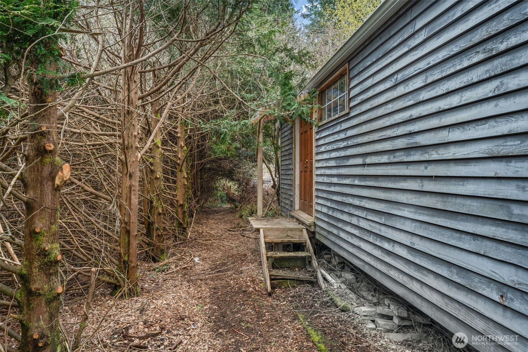 Side yard with mature landscaping and private pathway along the home. Opportunity to enhance outdoor access and usability.