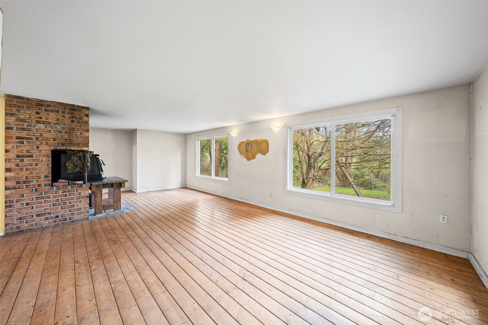 Living room features updated vinyl windows bringing in natural light and showcase peaceful, wooded views. Generous space ready for renovation and reimagining into a modern living area.