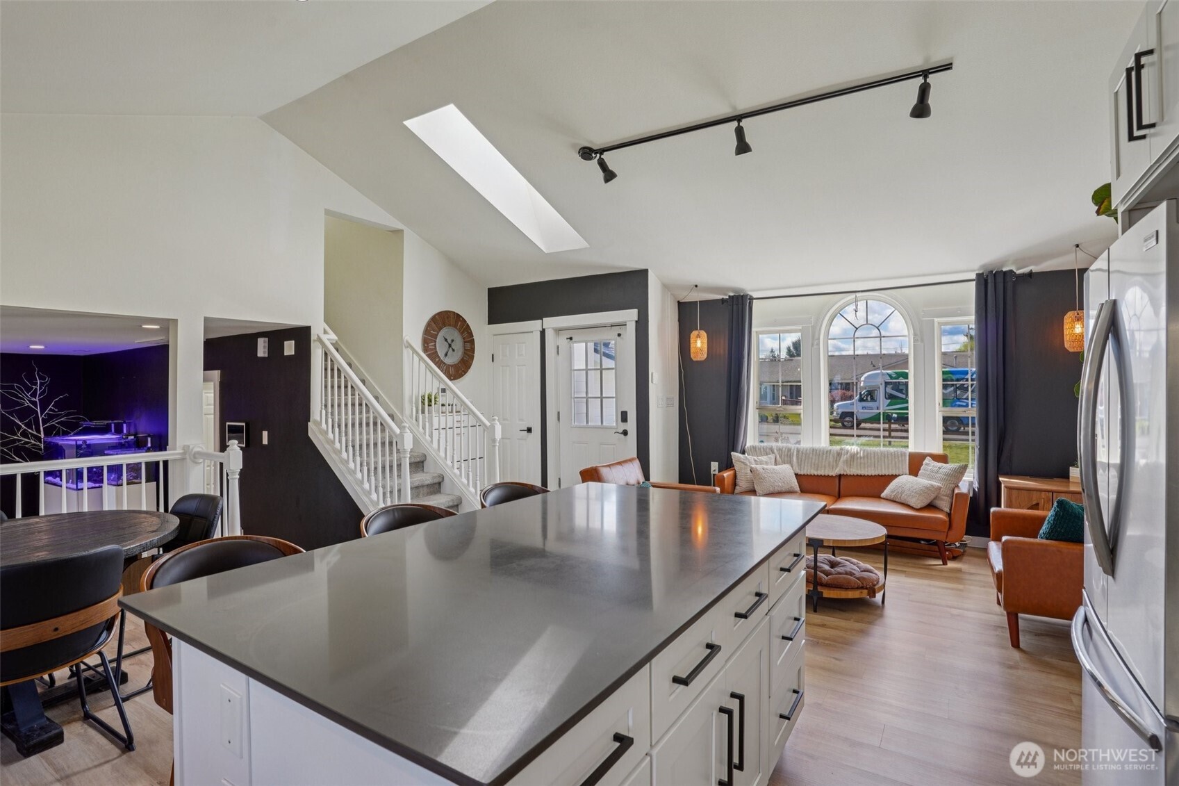 Updated kitchen features quartz countertops, custom cabinetry, stainless steel appliances, tile backsplash, and an oversized island.
