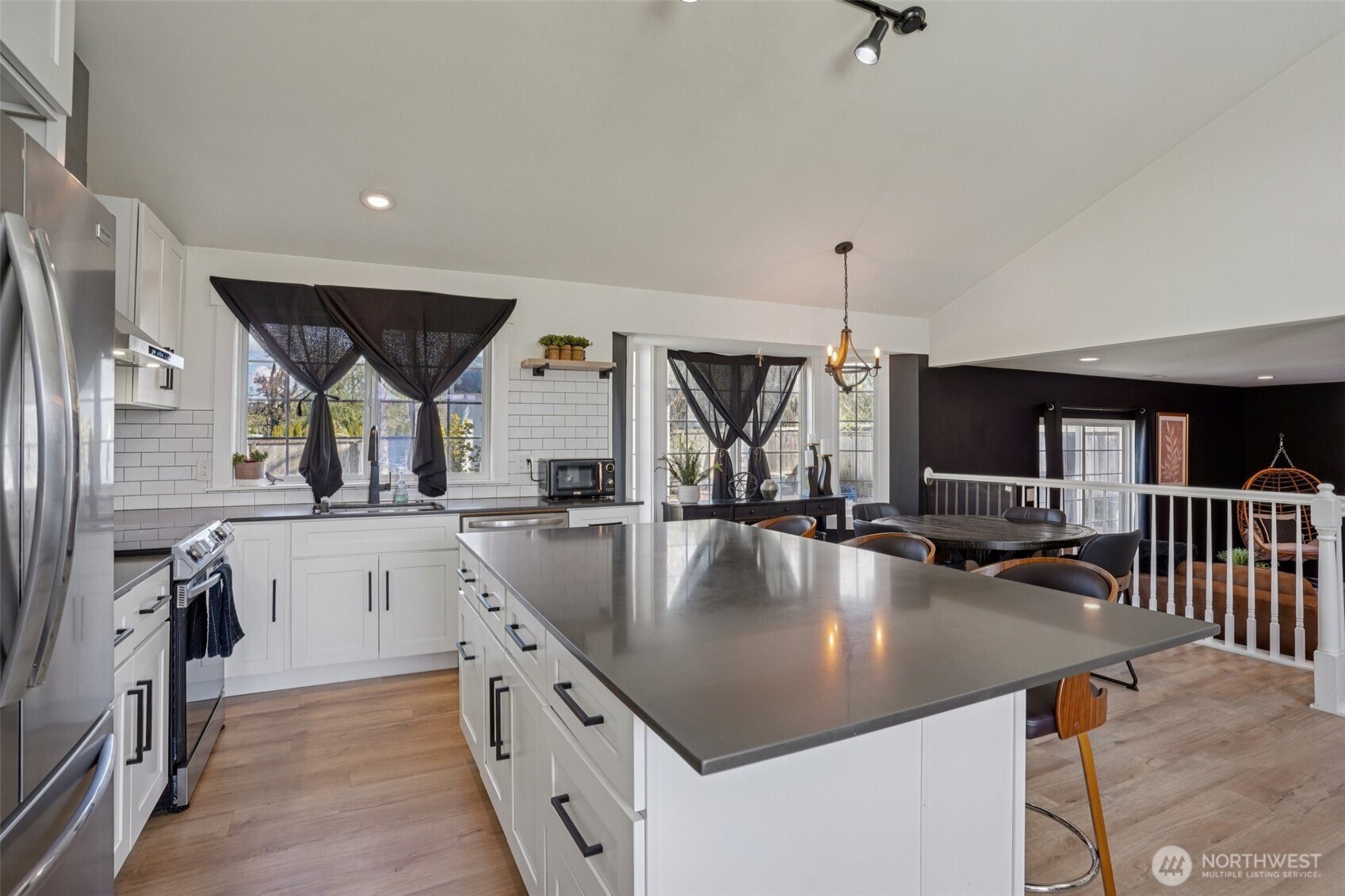 Updated kitchen features quartz countertops, custom cabinetry, stainless steel appliances, tile backsplash, and an oversized island.