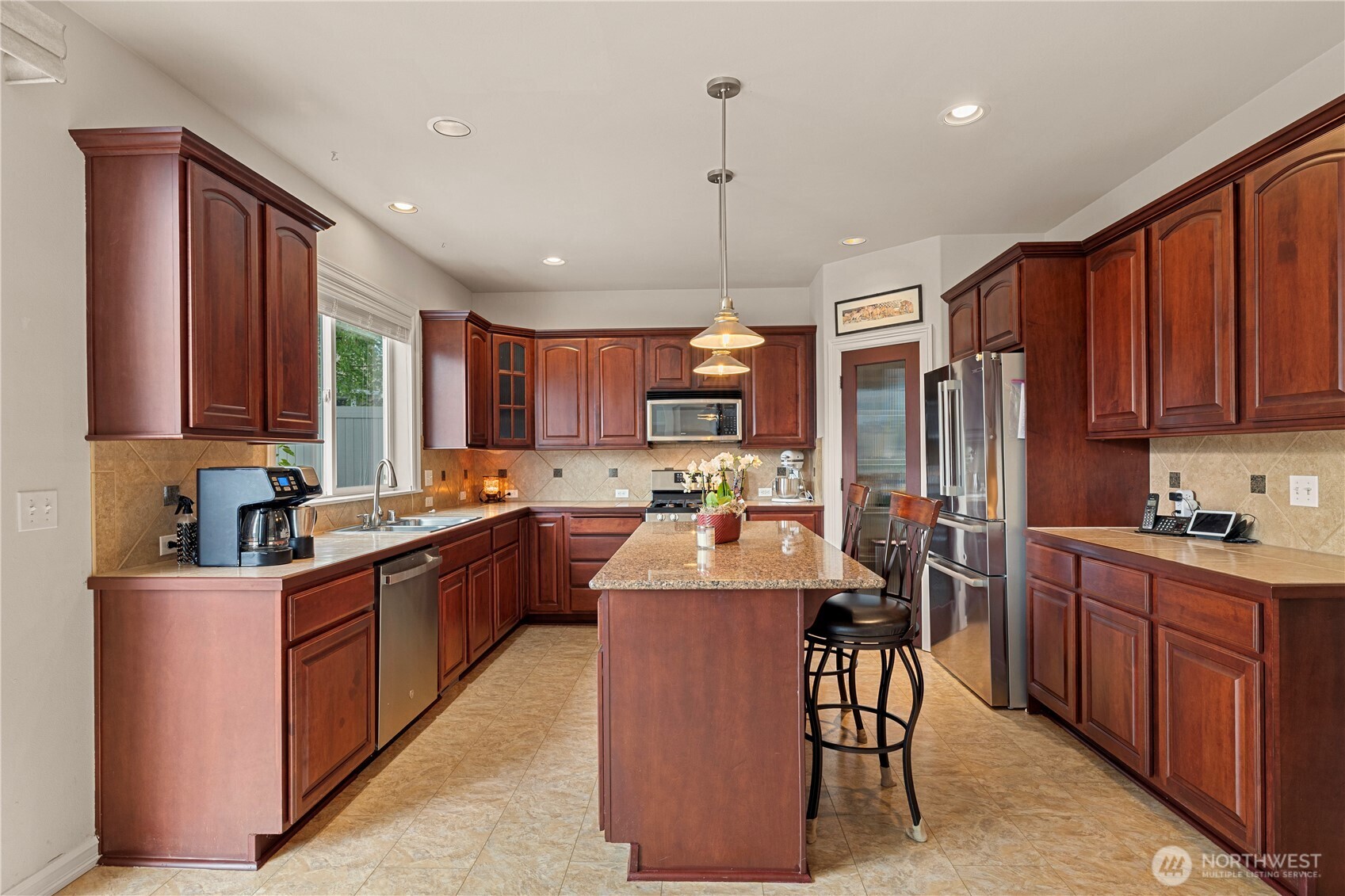 Kitchen is beautifully appointed with maple cabinetry, a center island, and slab granite countertops-perfect for everyday living and entertaining
