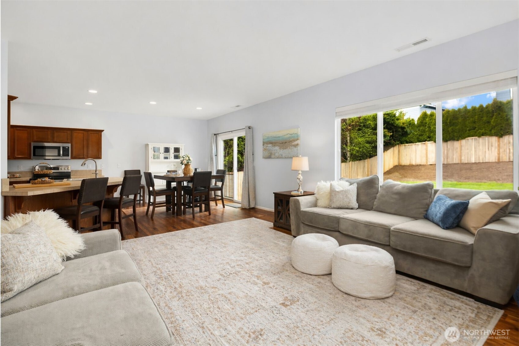 Centered around a warm fireplace and designed with generous scale, this gathering space offers the kind of comfort that invites people to linger. Natural light, rich flooring, and an airy sense of openness create an atmosphere that feels both elevated and easy. Whether hosting friends or enjoying a quiet night in, this is a room made for connection, conversation, and everyday moments that feel a little special.