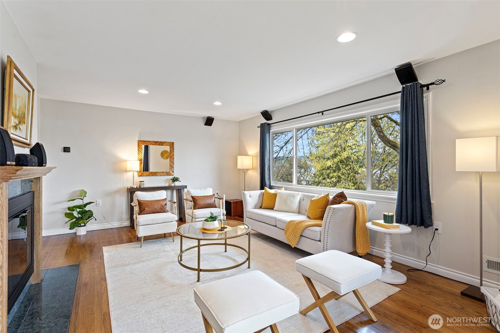 Light-filled living room featuring newer windows, refinished oak flooring, and fresh paint for a warm, inviting feel.