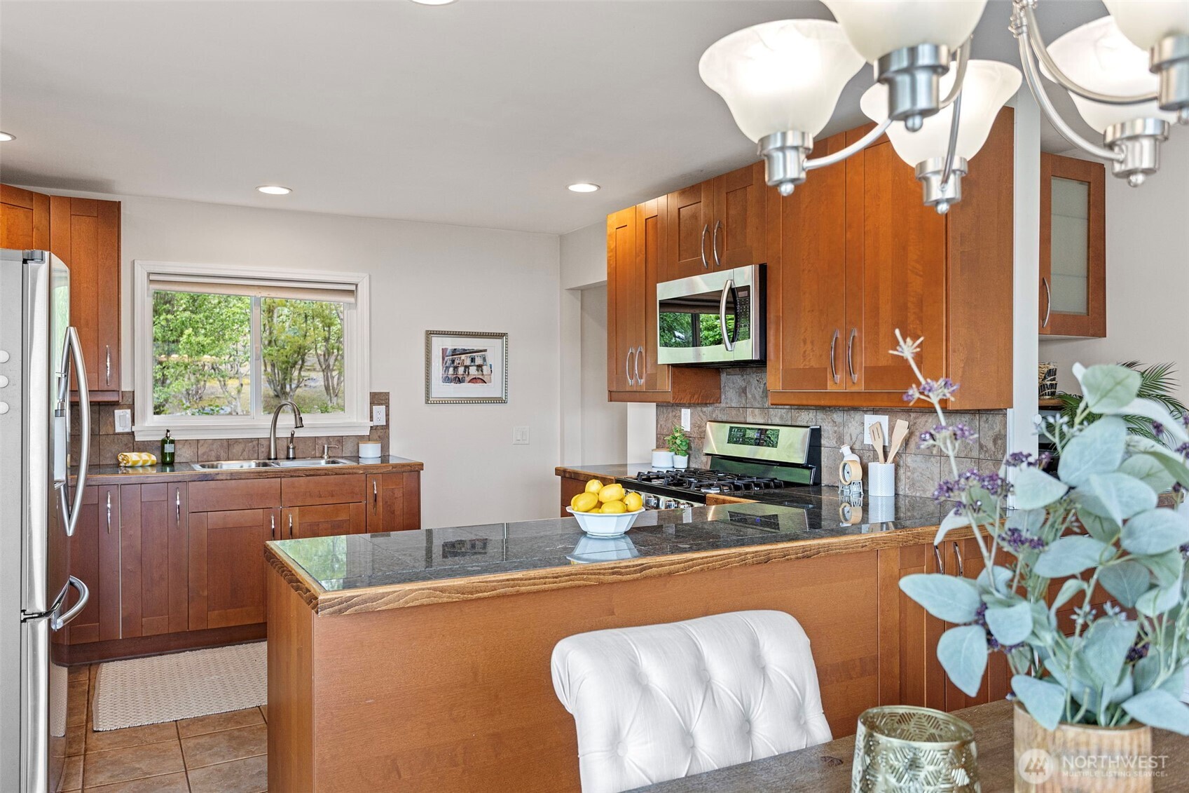Chefs kitchen with an abundance of cabinets, granite counters under-cabinet lighting, tiled flooring and a tiled backsplash.