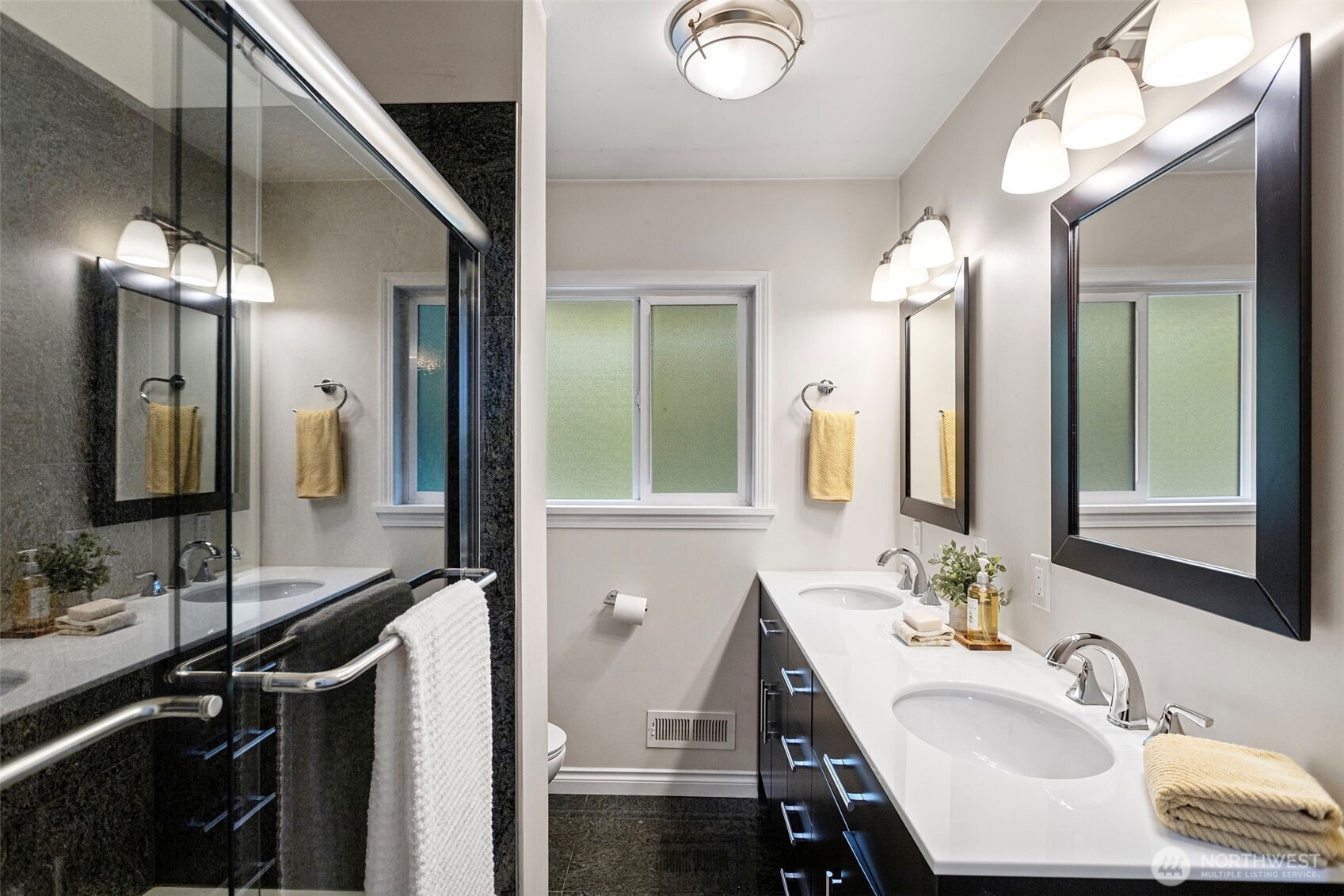 Full bathroom on main level features a double quartz vanity, granite bath surround, glass shower doors and stainless hardware.