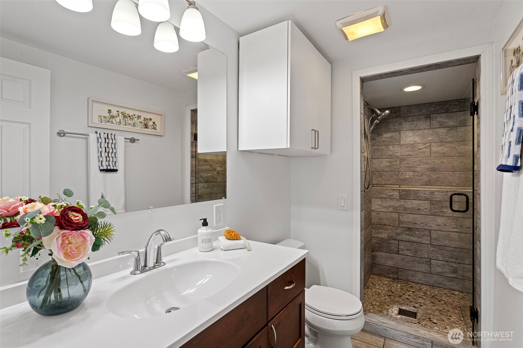 Bathroom on lower level— featuring a walk-in shower with beautiful tiling, a built-in shelf for your shampoos and a pebble mosaic floor for maximum comfort with the soothing effect of pebbles on your feet