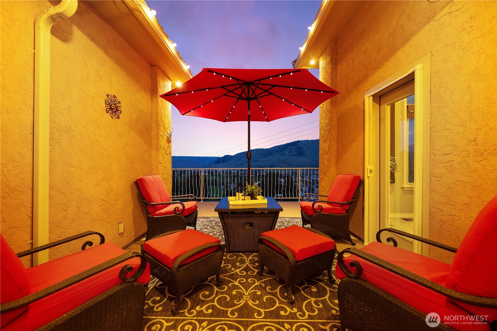 Charming and private outdoor patio retreat designed for relaxation and intimate gatherings. Framed by warm stucco walls, this inviting space features comfortable seating beneath a vibrant umbrella, creating a cozy setting to unwind while enjoying beautiful lake and mountain views. Perfect for morning coffee or evening conversation, this tucked-away patio offers a peaceful extension of the home’s outdoor living spaces.