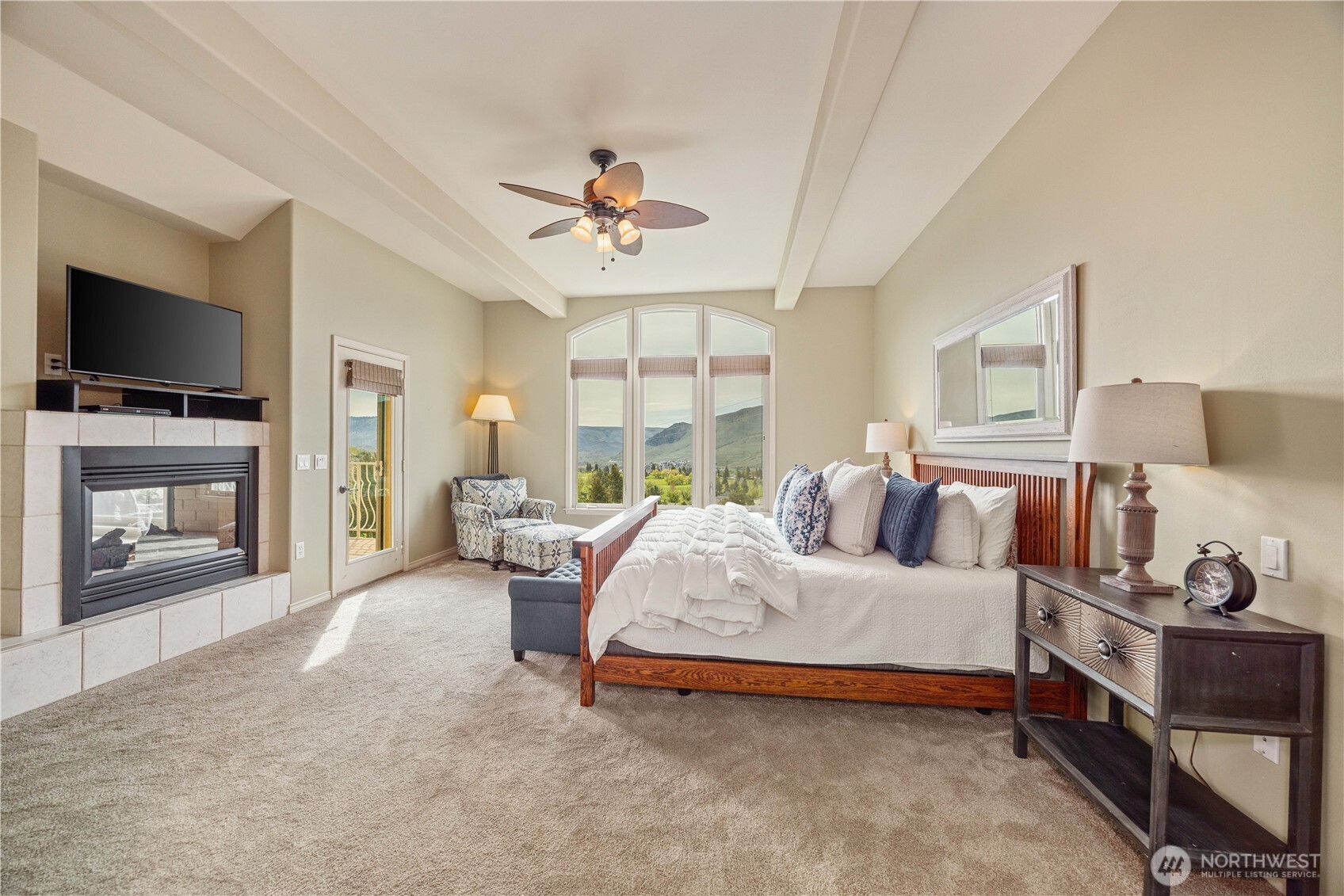 Luxurious primary suite designed as a private retreat, featuring generous proportions, soaring ceilings, and abundant natural light. Expansive windows frame serene views, while the spacious layout easily accommodates a sitting area for added comfort. The elegant design is complemented by a cozy fireplace, creating a warm and relaxing ambiance. Thoughtful finishes and a tranquil atmosphere make this suite the perfect place to unwind at the end of the day.