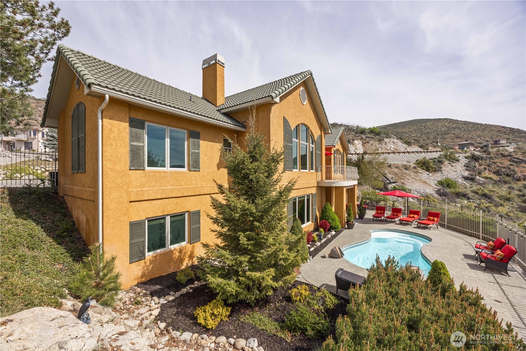 Beautifully designed exterior set against a scenic hillside backdrop, this home offers exceptional outdoor living and privacy. The expansive patio surrounds a sparkling in-ground pool, creating the perfect setting for entertaining, relaxing, and enjoying warm summer days. Lush landscaping and thoughtfully placed greenery enhance the natural surroundings, while multiple outdoor seating areas invite you to take in the peaceful views. This inviting outdoor space is ideal for embracing the best of indoor-outdoor living.