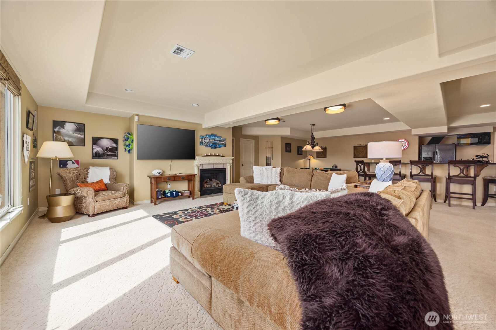 Inviting lower-level living area designed for both comfort and entertaining, featuring a spacious seating area and open-concept layout. The well-appointed wet bar provides the perfect setup for hosting guests, complete with ample counter space and storage. Large windows bring in natural light while capturing scenic views, enhancing the warm and welcoming atmosphere. Ideal as a media room, game space, or guest retreat, this versatile area offers the perfect blend of function and relaxation.