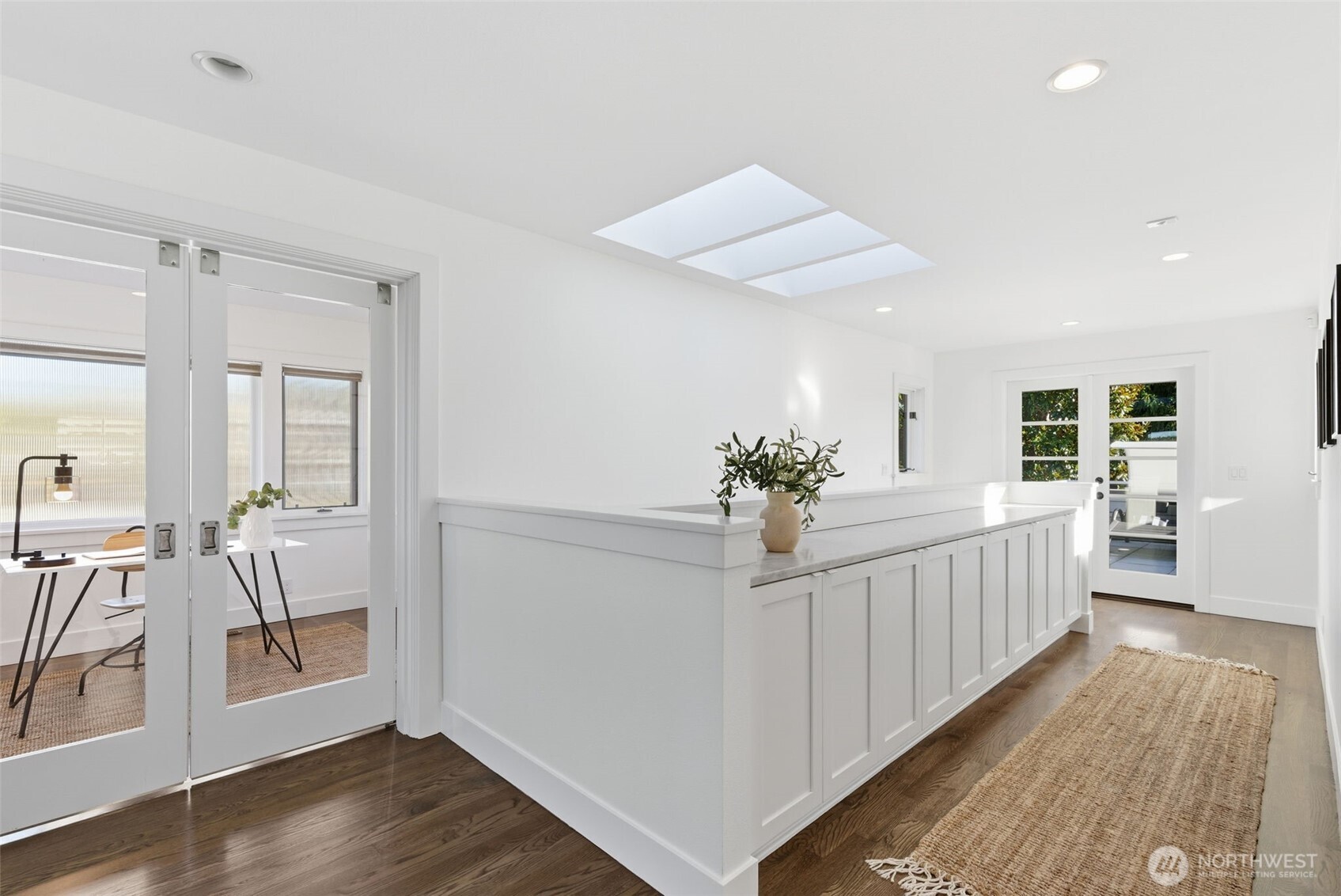 Upstairs, French doors to a large deck; a highly functional run of storage cabinets topped with Carrara marble; and access to both the den/studio/nursery and the primary suite.