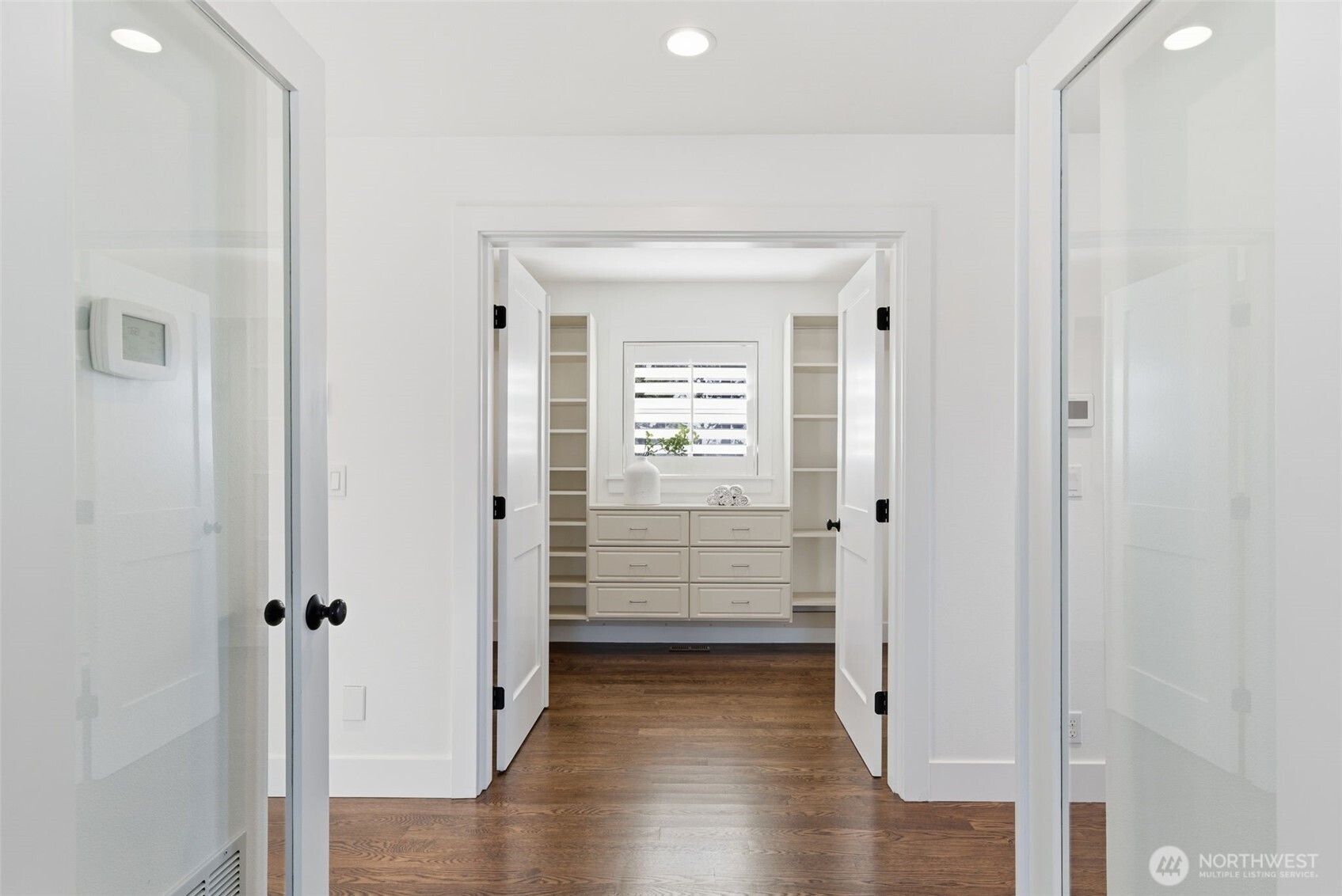 Double French doors lead to the primary suite, as well as the walk in closet. There is a separate thermostat here for the upper zone heating/cooling system. The keypad to the right is for the Bosch wired security system. The home also benefits from a central vacuum, including a brand new (still in box) accessories kit.