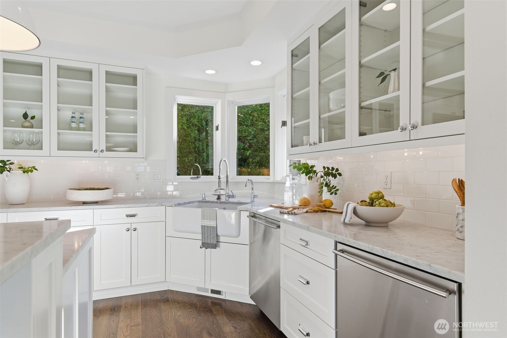 Authentic Carrara Marble countertops and a pair of Bosch dishwashers makes clean up and entertaining a breeze. Upper cabinets with glass fronts add softness and reflection, perfect for displaying both beautiful serve ware and everyday dishes. The Rohl Shaws apron-front sink, handmade in England, perfectly punctuates the space. There is also a dedicated filtered water faucet here, with replaceable Everpure filter under the sink.