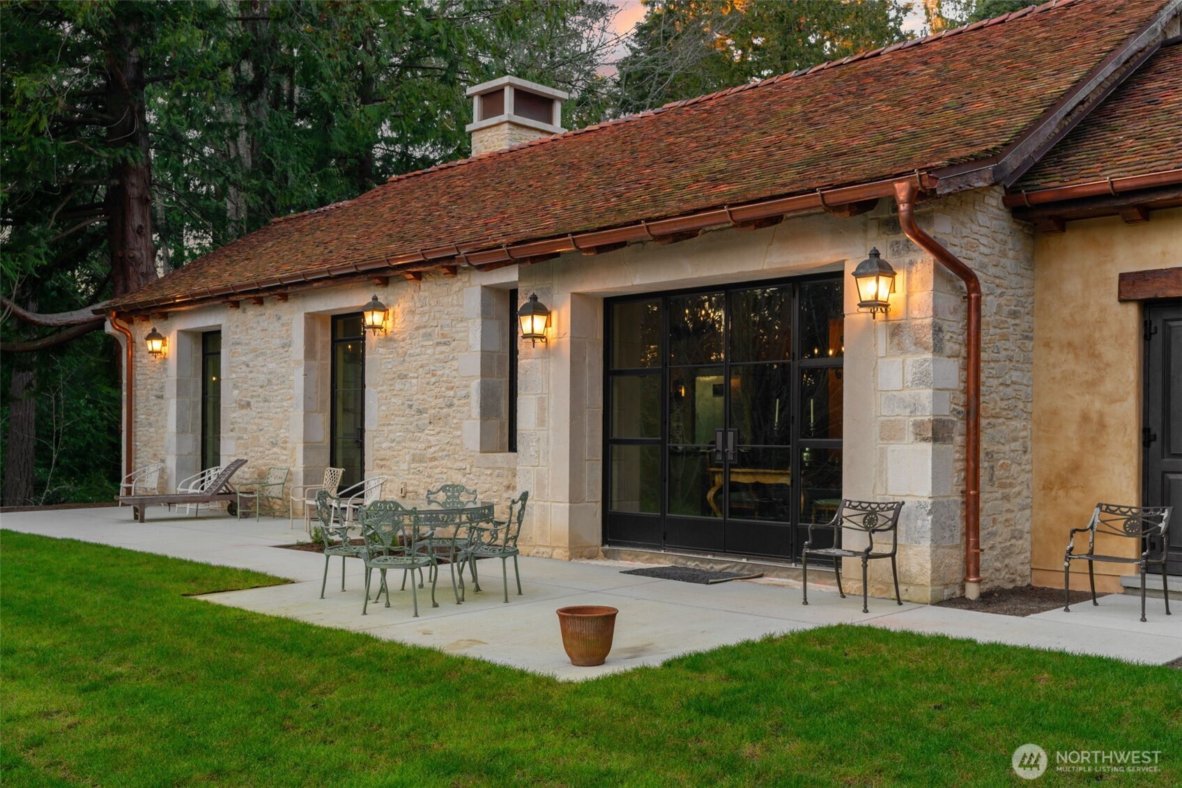 The rear patio unfolds in classic European fashion, framed by natural stone and designed for effortless indoor-outdoor dining.