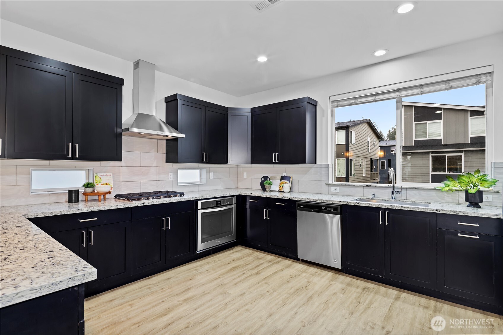 Large format Subway tile backsplash with SS hood vent gas range Quarz slab counters