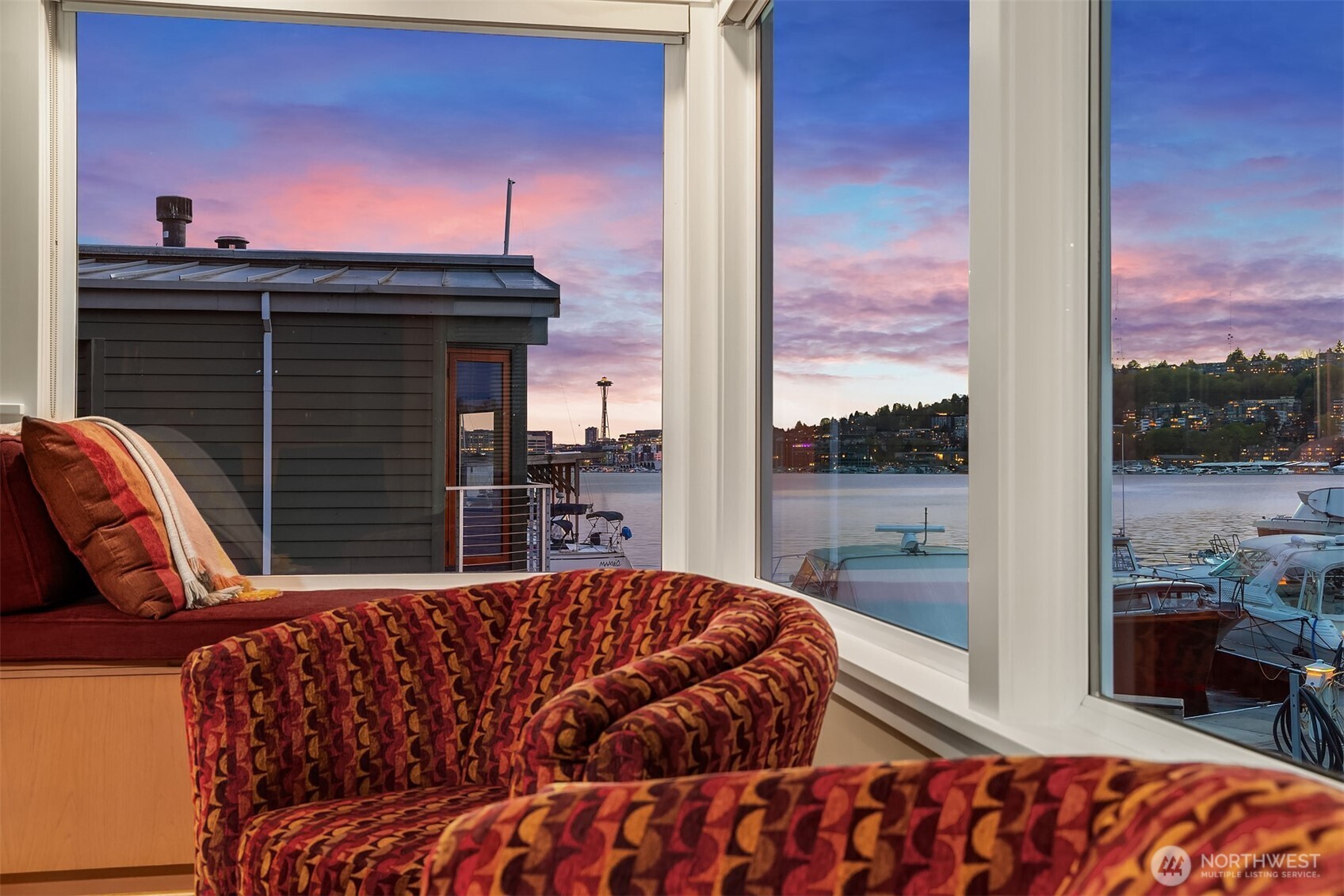 From the window seat, the Space Needle and Queen Anne lights come up under a streaky pink sky — a nightly, free show.