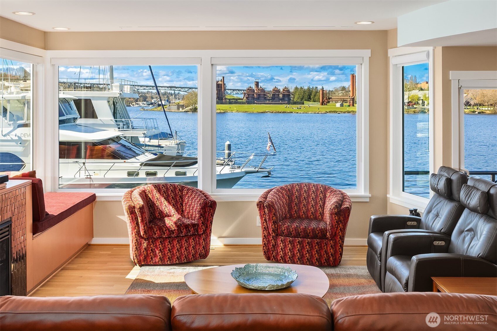 Corner windows wrap the living room in water and sky; a built-in window seat with storage runs beneath the glass.