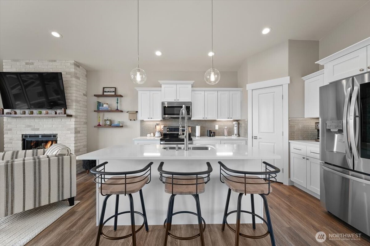 Bright upper-level kitchen featuring quartz countertops, quality cabinetry, stainless appliances, and generous gathering space around the oversized island.