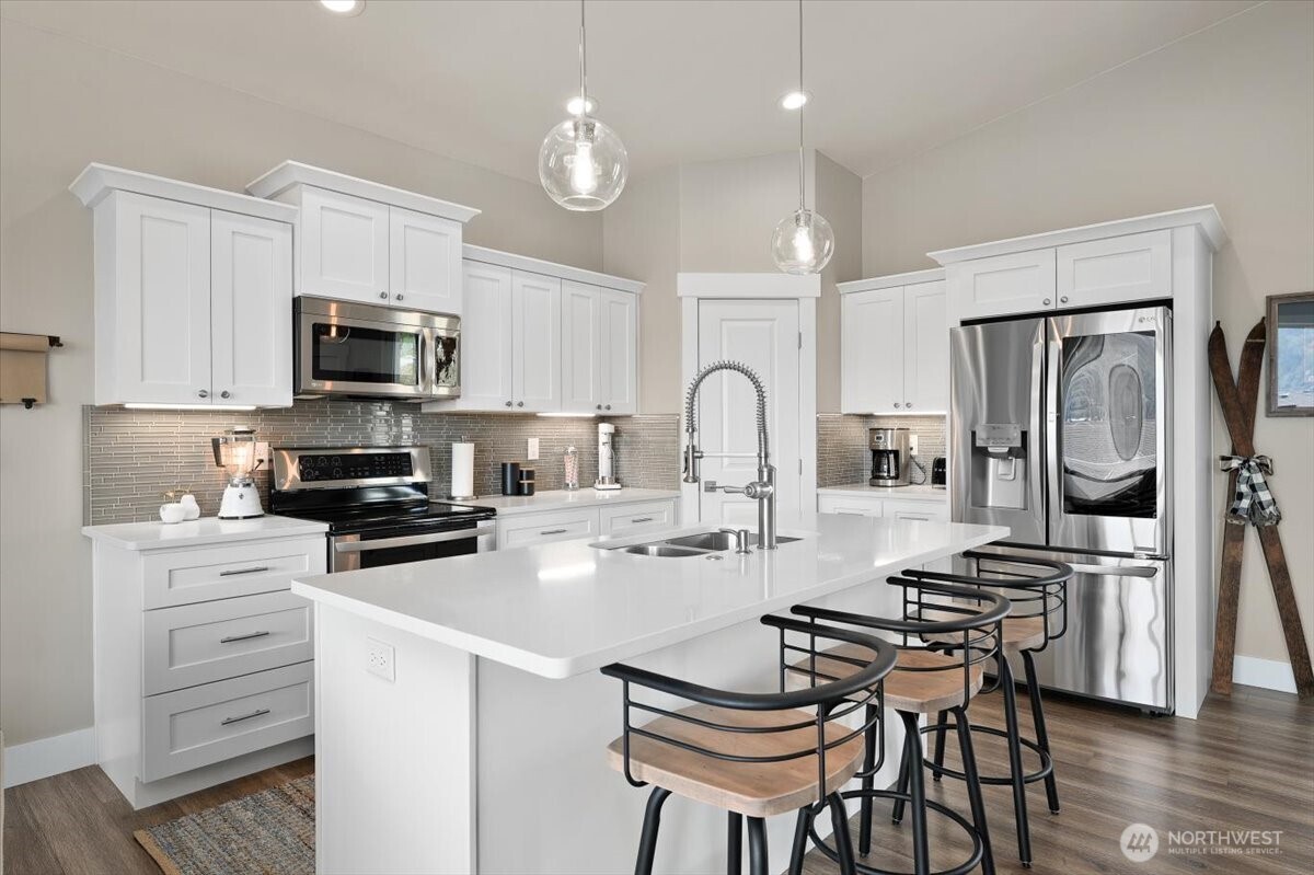 Layered lighting, clean finishes, and oversized island seating give the kitchen a warm and inviting atmosphere.