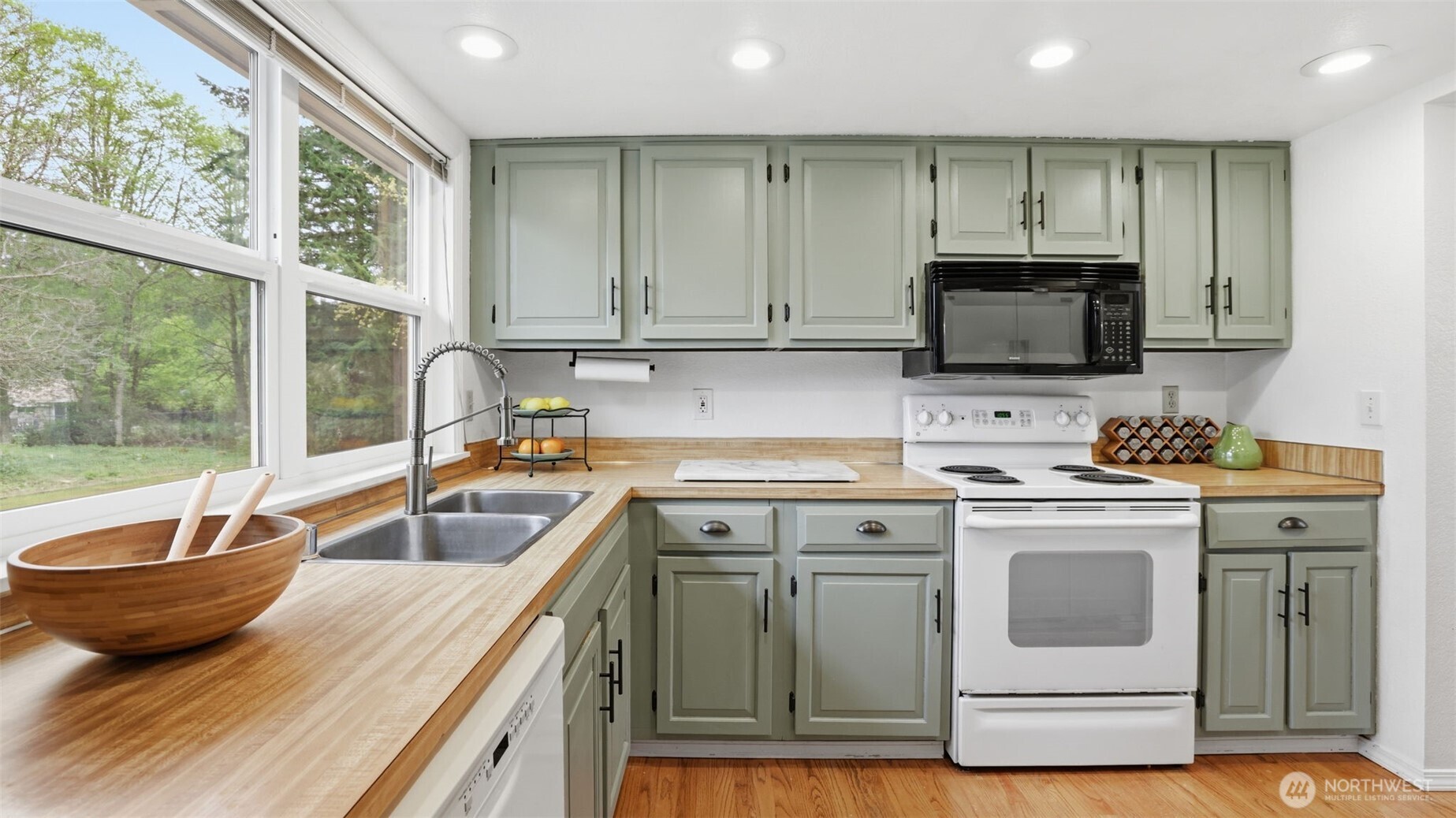 Large windows, newer appliances, and painted cabinetry provide a modern farmhouse look to this kitchen.