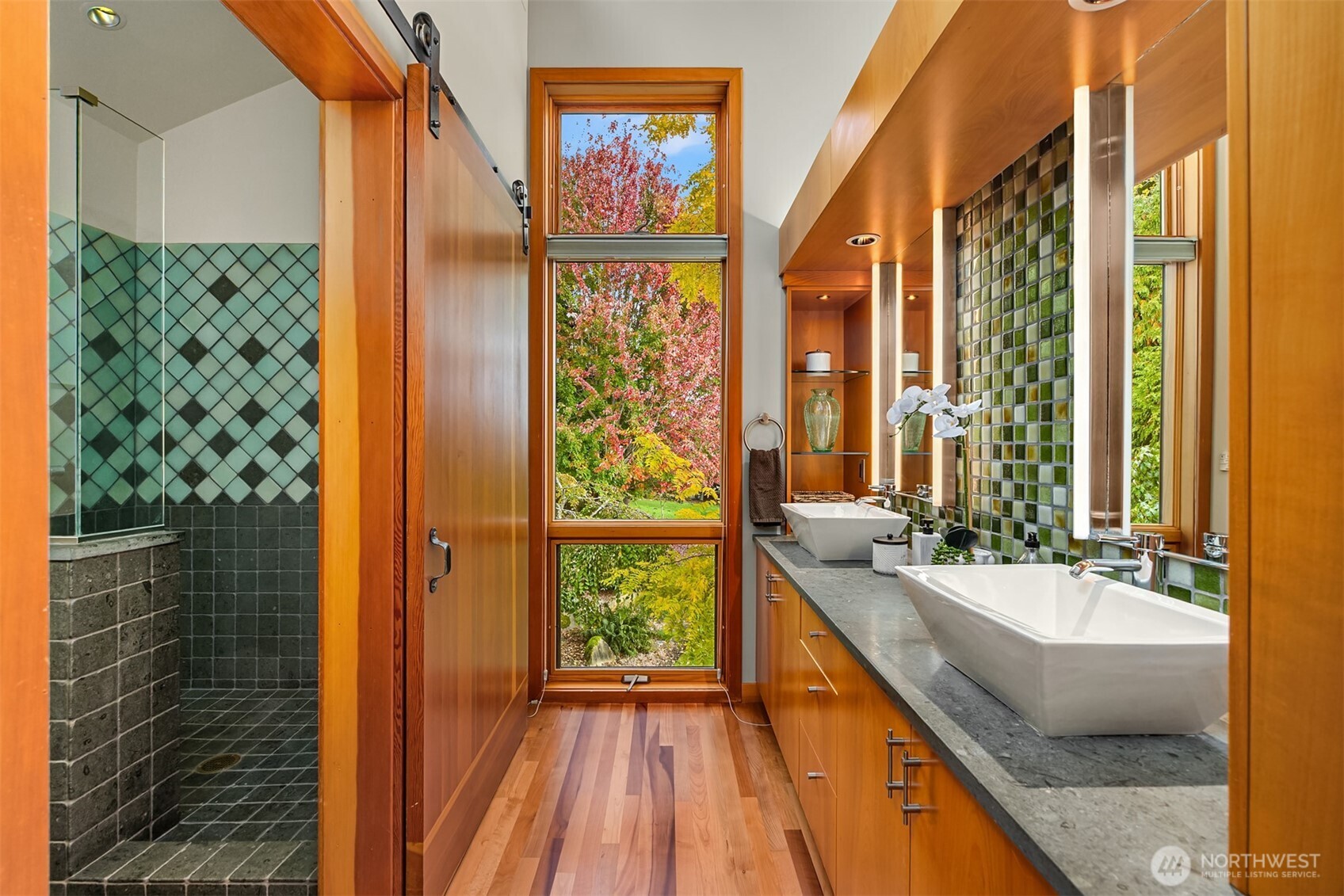 The eco-luxury ensuite bathroom features double sinks, German greenstone countertop, walk-in shower with recycled glass and greenstone tile, Dorn Bracht fixtures, walk-in closet, and custom solid-fir barn doors for privacy.
